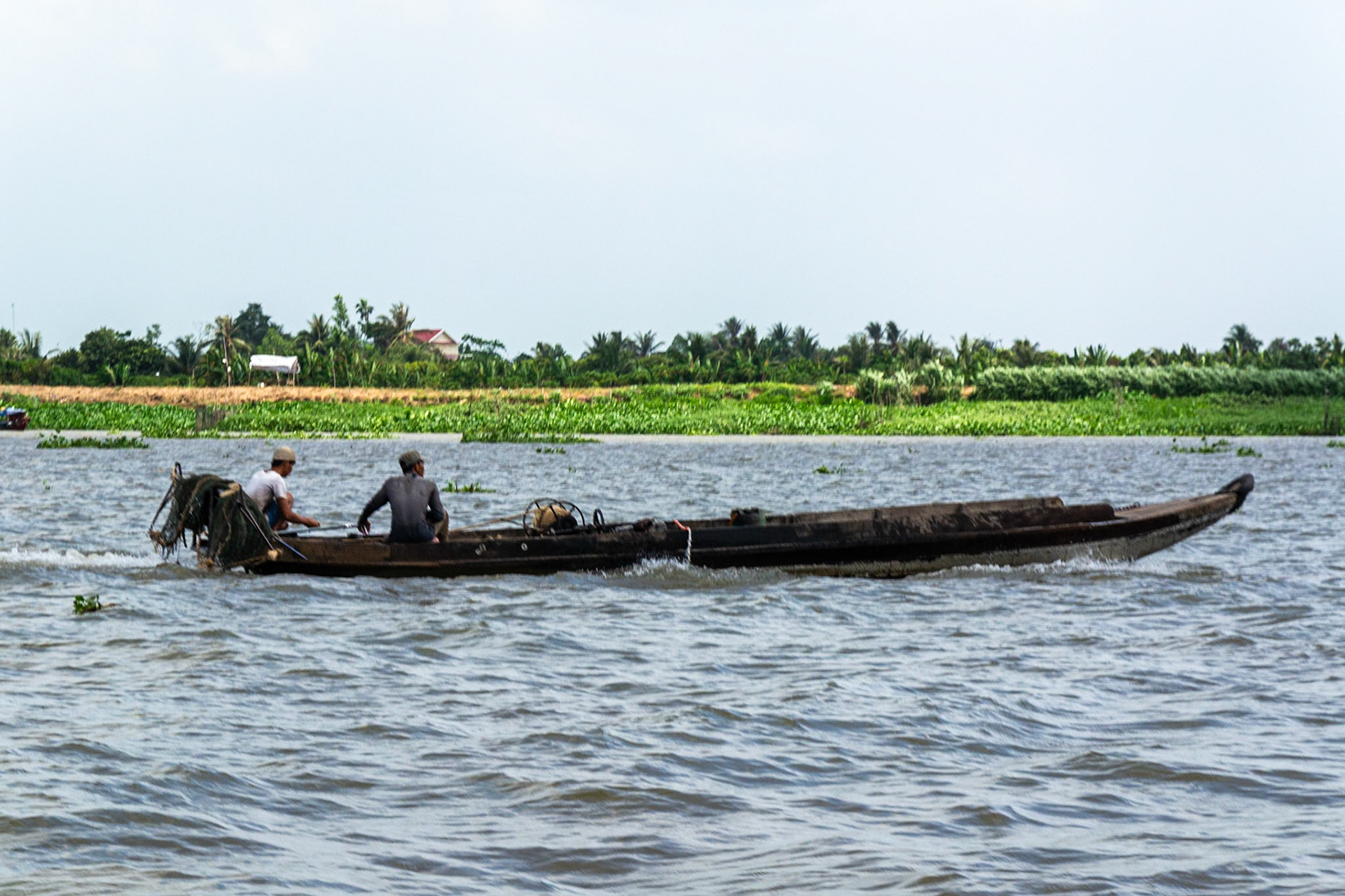 River traffic of all types and sizes ply the waters of the Mekong Delta., here a longboat fishing trawler.