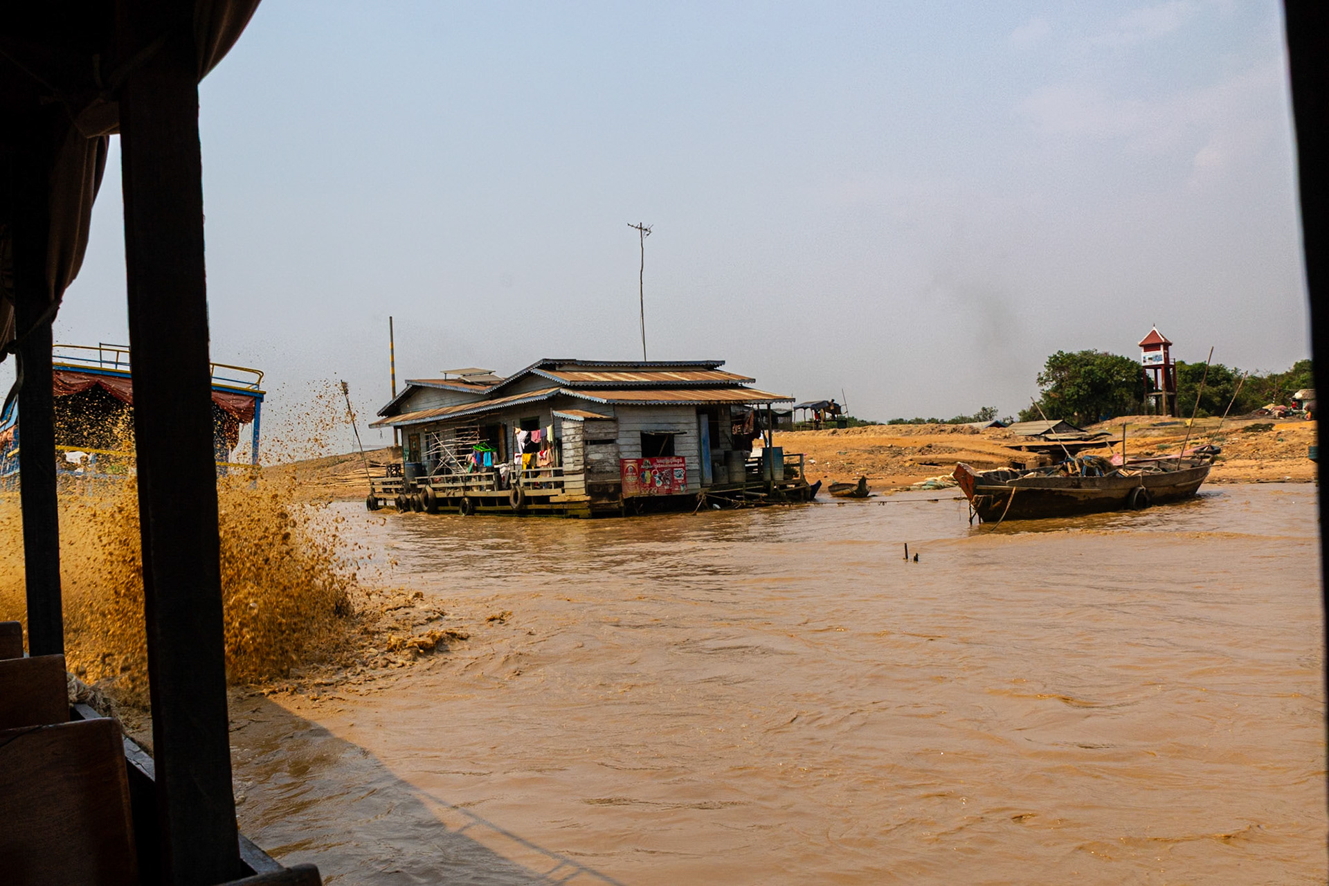 Muddy spray erupts behind us as our boat forces its way through the shallow water.