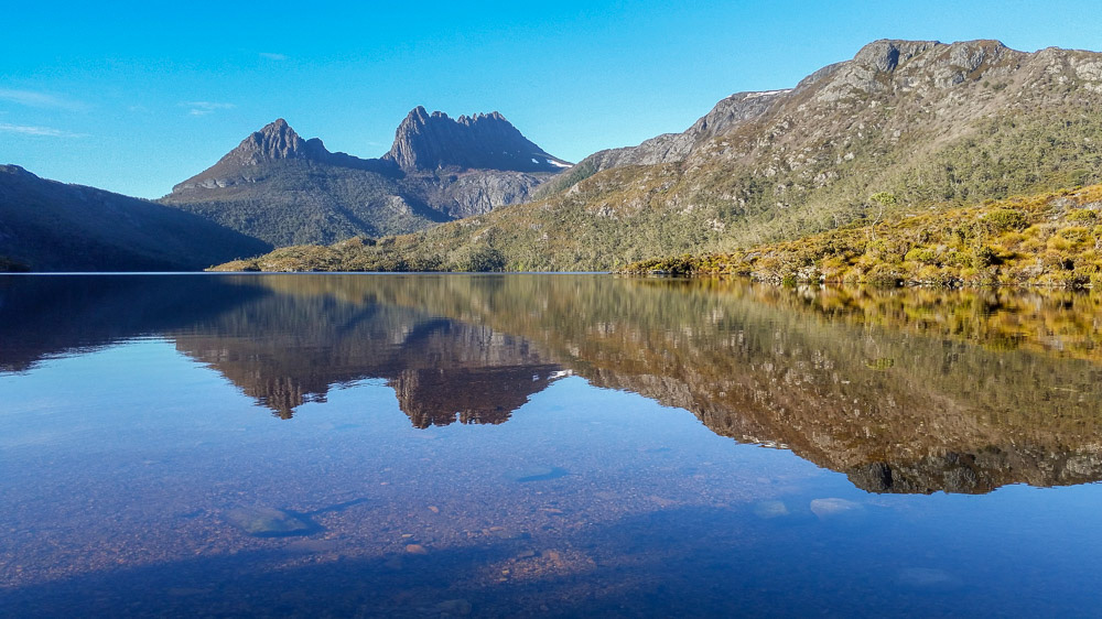 Early the next morning Cradle Mountain is reflected in the mirrored surface of Dove Lake.