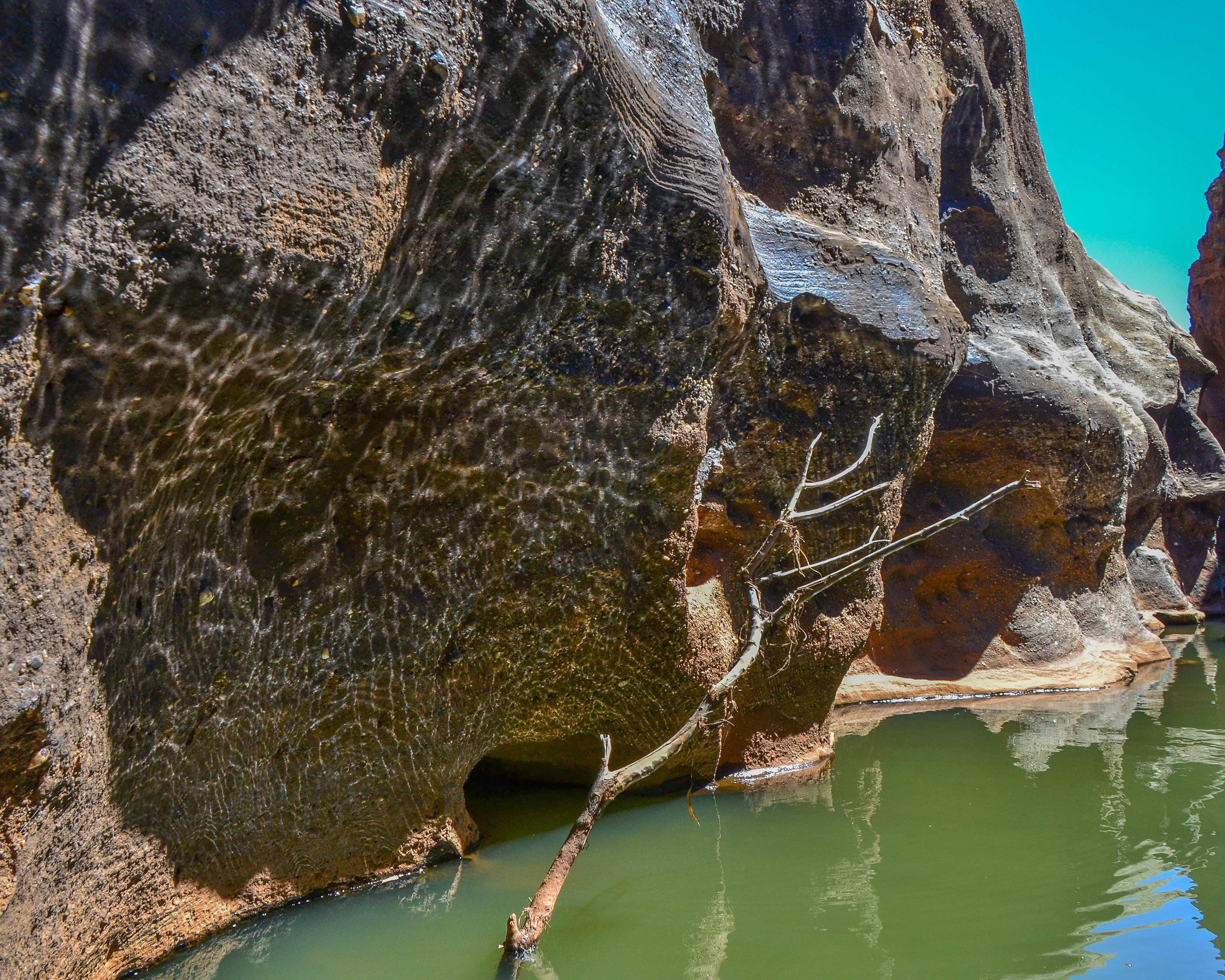 Light reflected by the waterr's surface projects a lacelike pattern on the rockface.