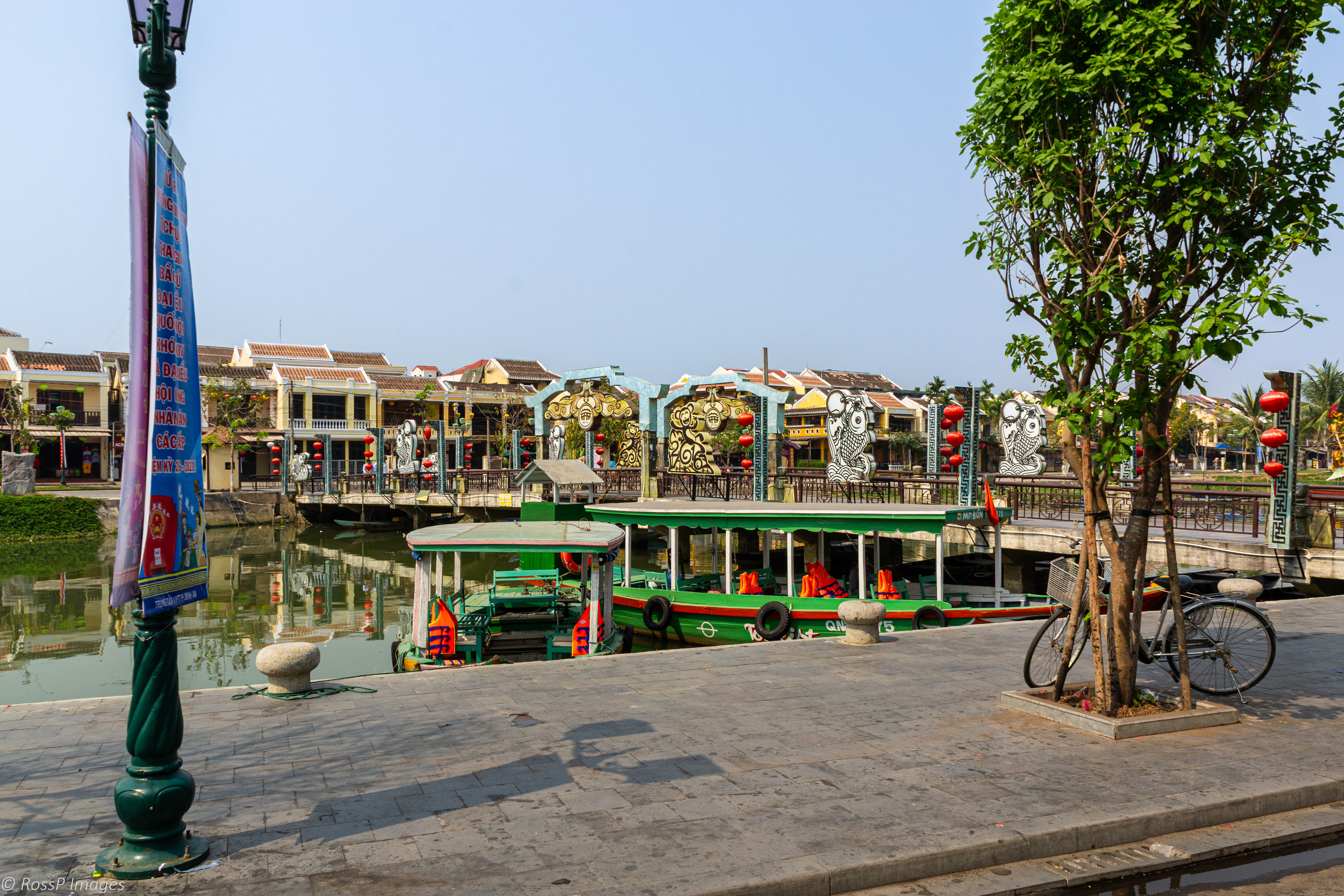 Tourist boats anchored in front of the pedesrtian bridge over Thu Bon River.