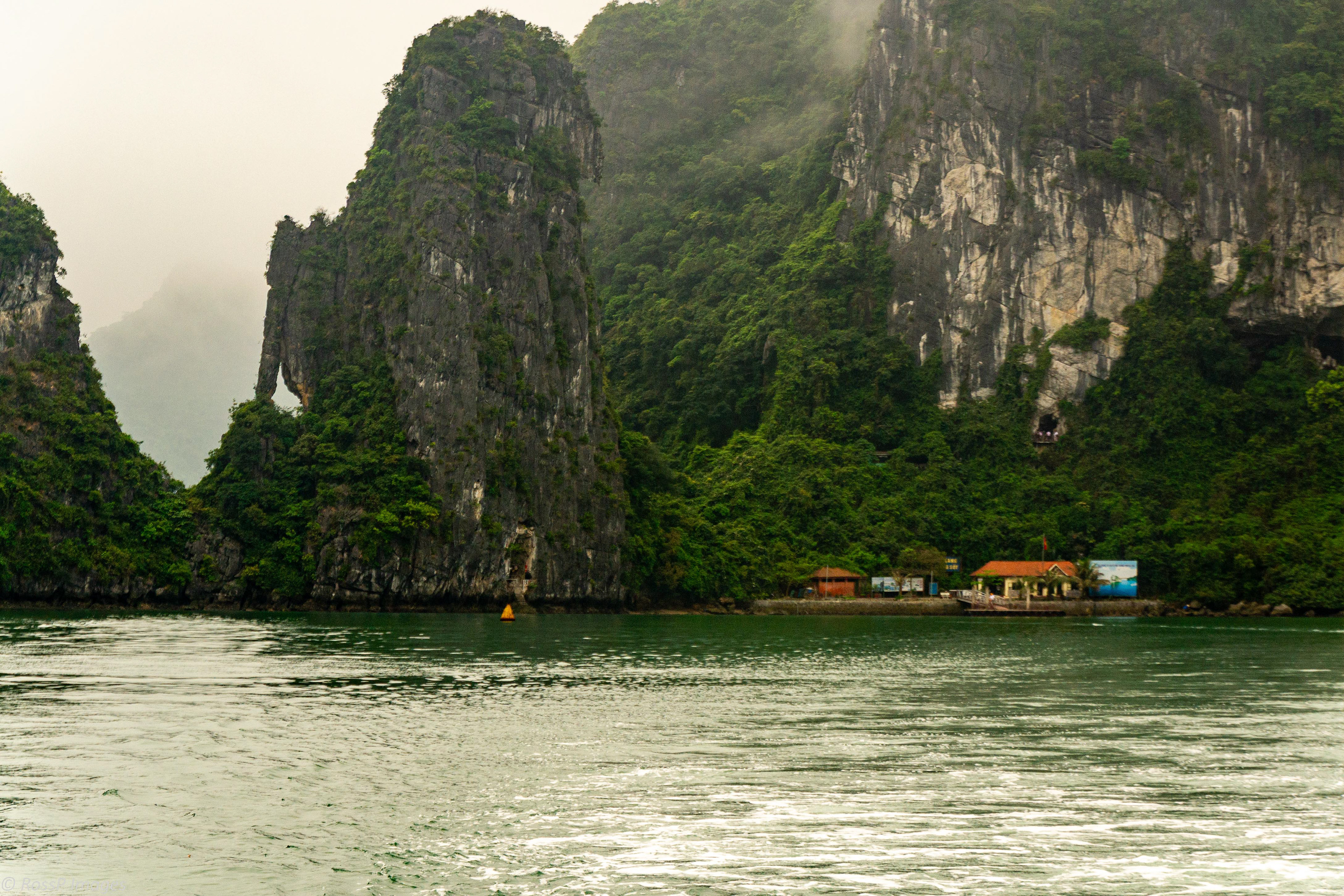 Approaching Hang Sung Sot cave - the grotto entrance can be spotted 25 metres above the jetty buildings.