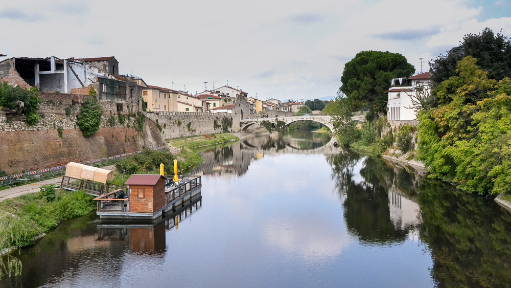 The Bisenzio (river), a tributary of the Arno, flows adjacent the 14th century walls of the old city.