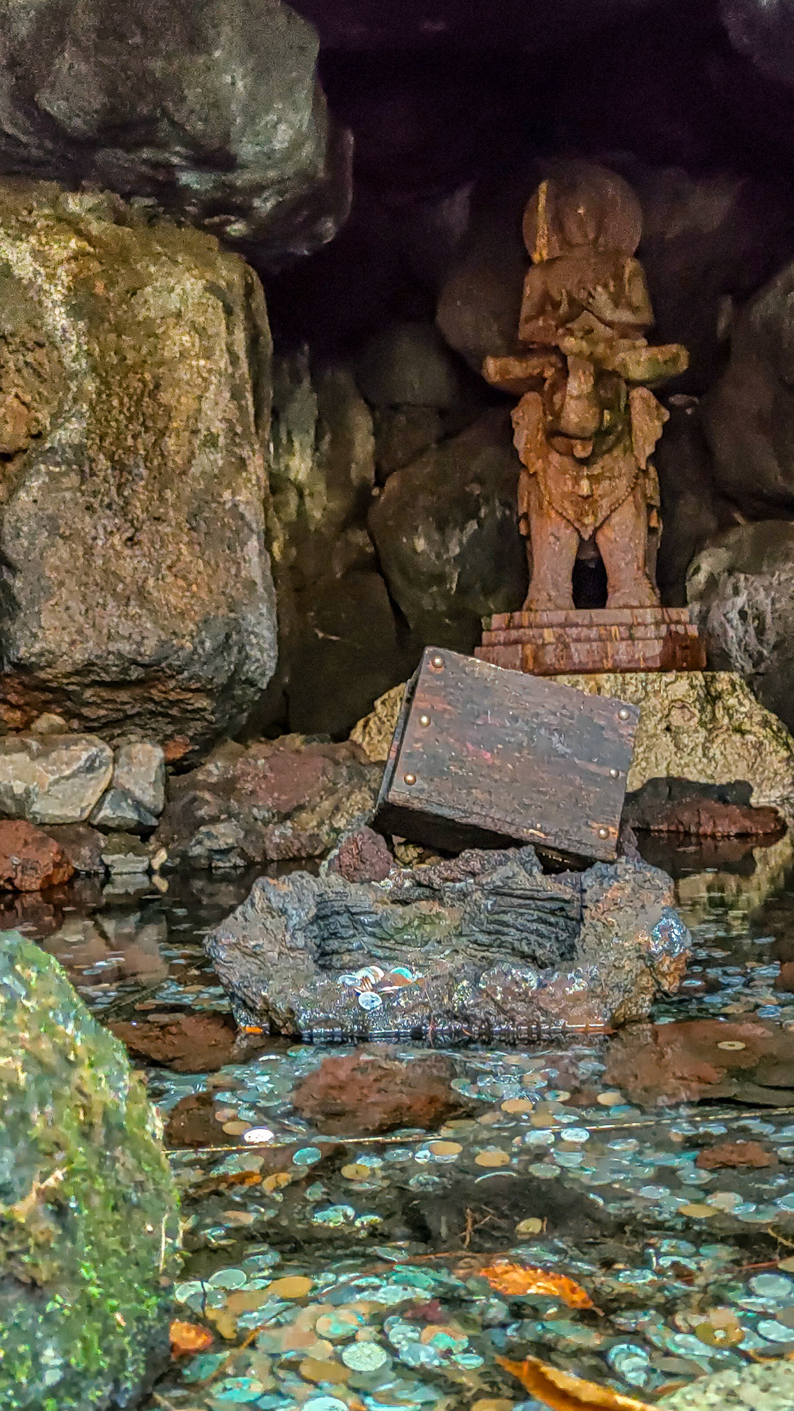 Coins lie at the base of a stone idol, a Buddhism diety astride an elephant inside the grotto.