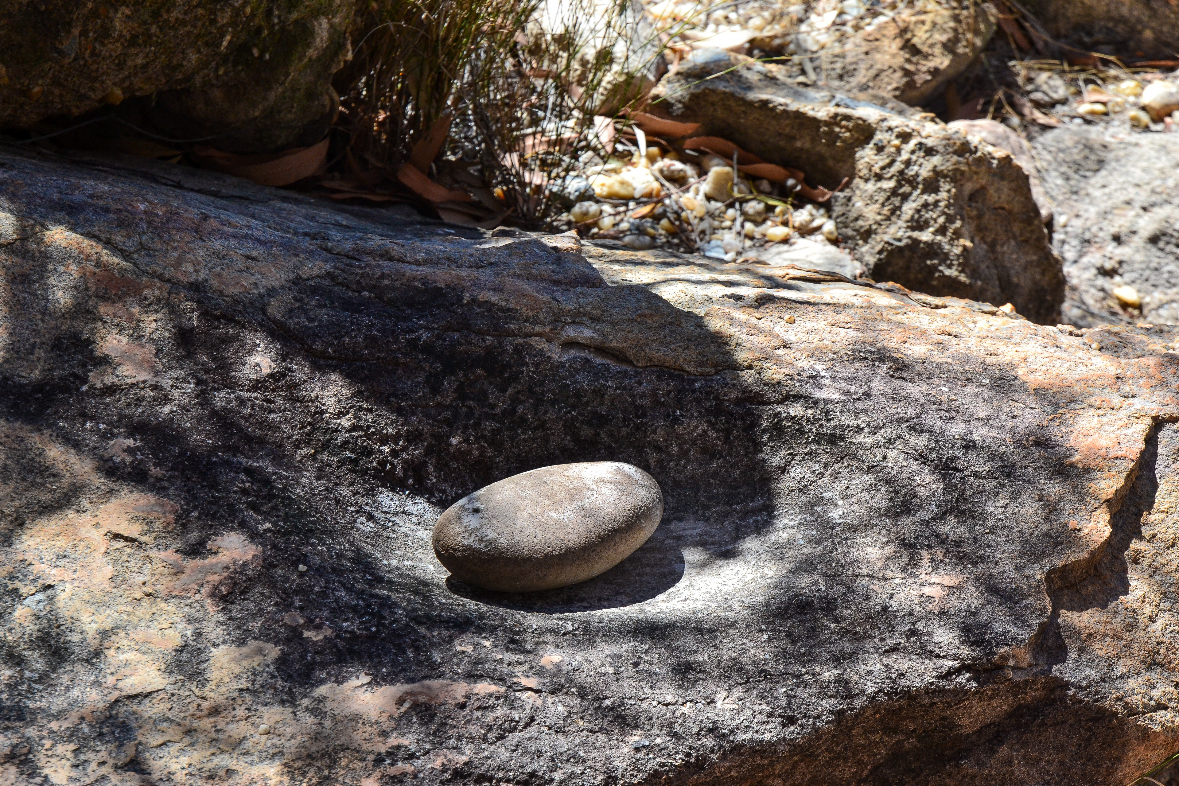 A worn depression and grinding stone, an ancient mortar and pestle.