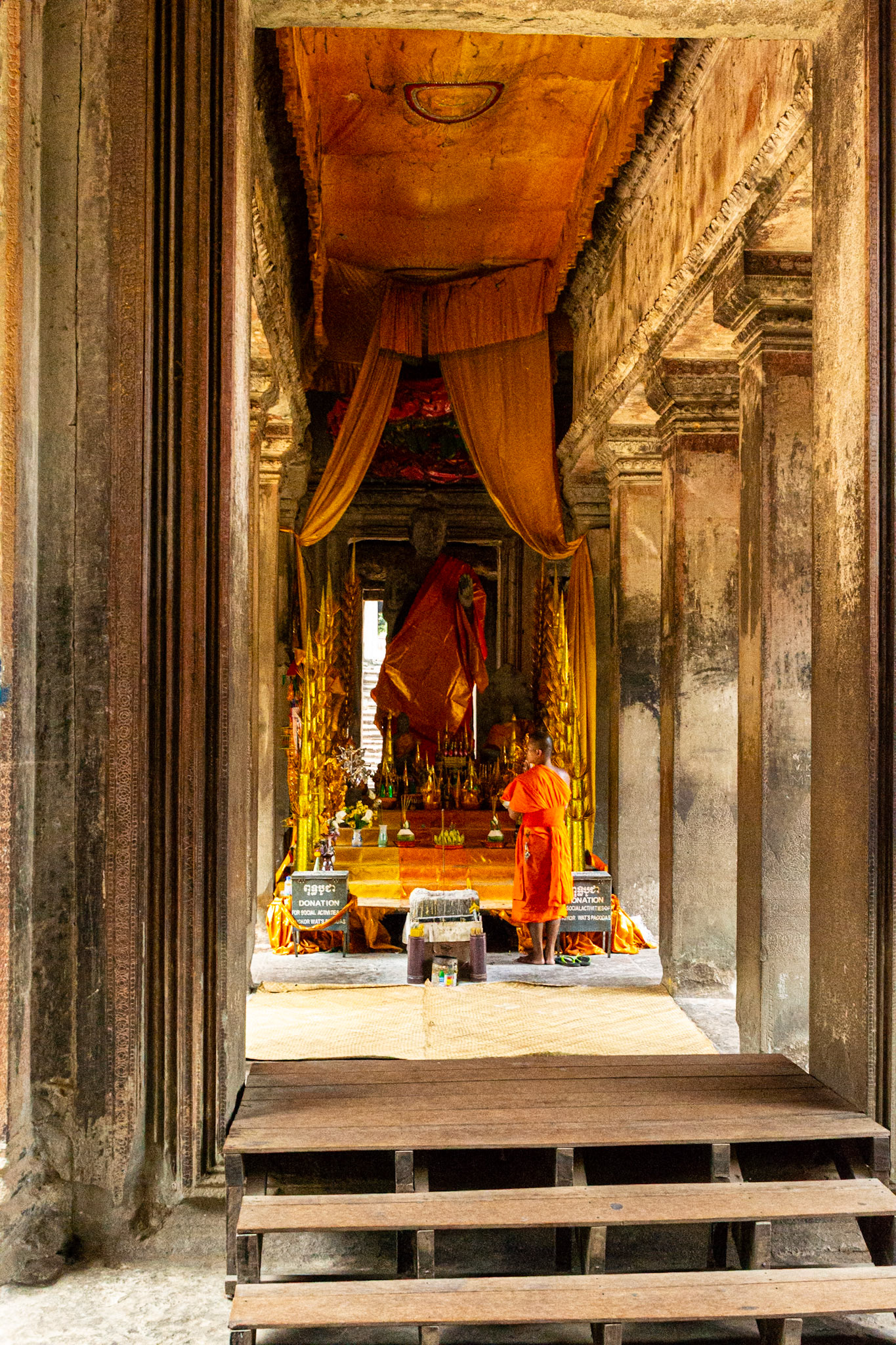 A Buddhist Monk passes in front of a shrine within the complex.