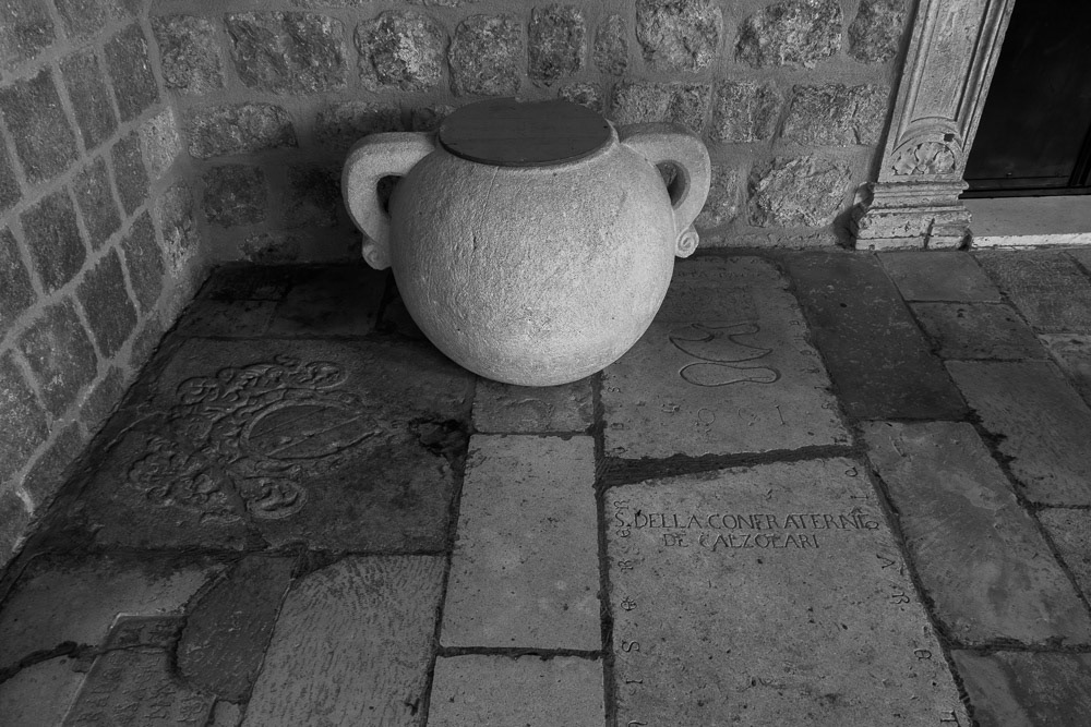 Franciscan Monastry - a medieval stone jar sits on enbossed paving slabs.