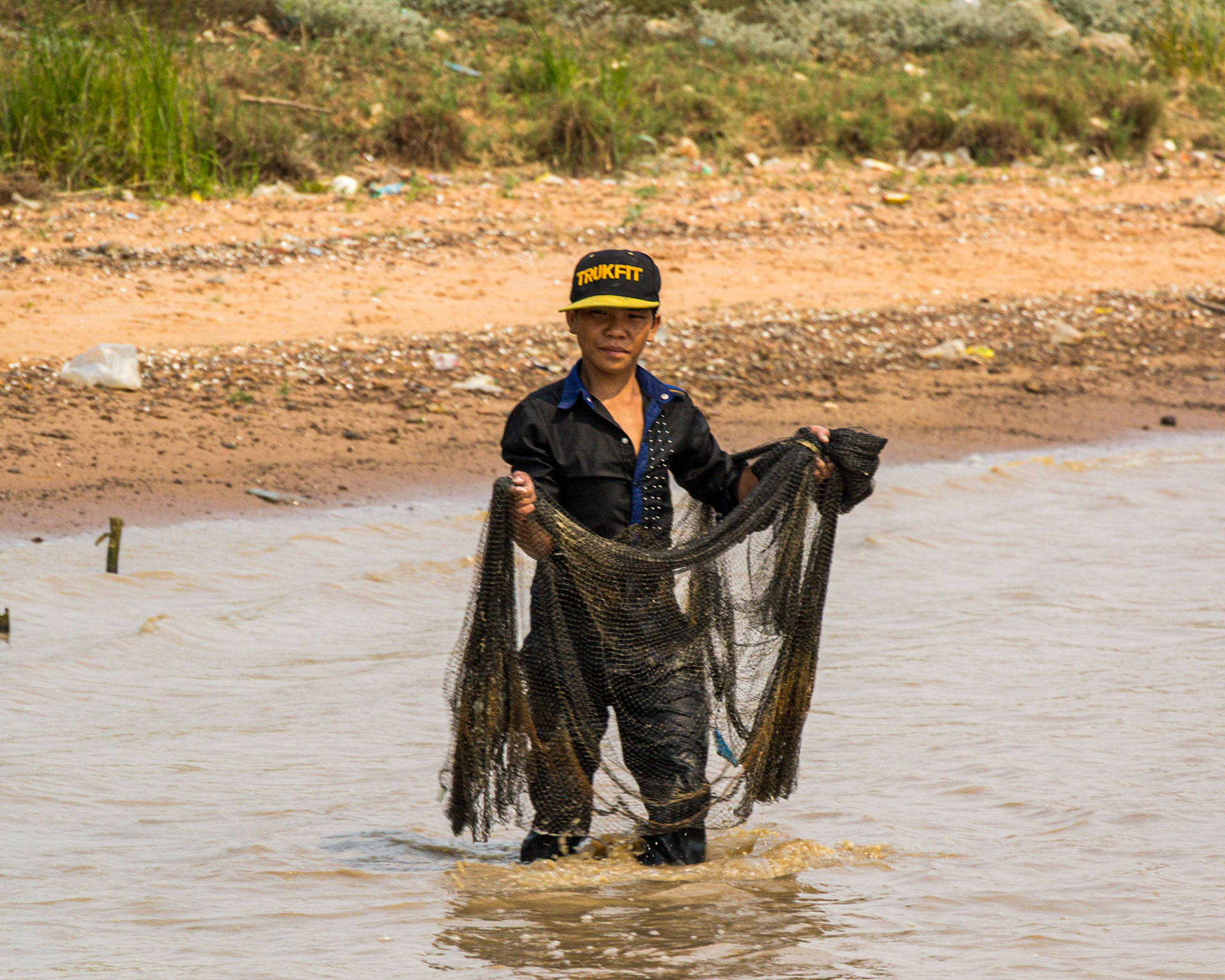 A local fisherman trying his luck in the muddy water.