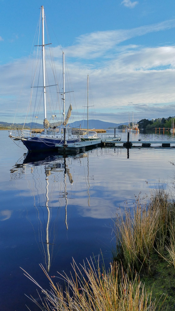 Reflections are mirrored in the dark, glassy calm waters.