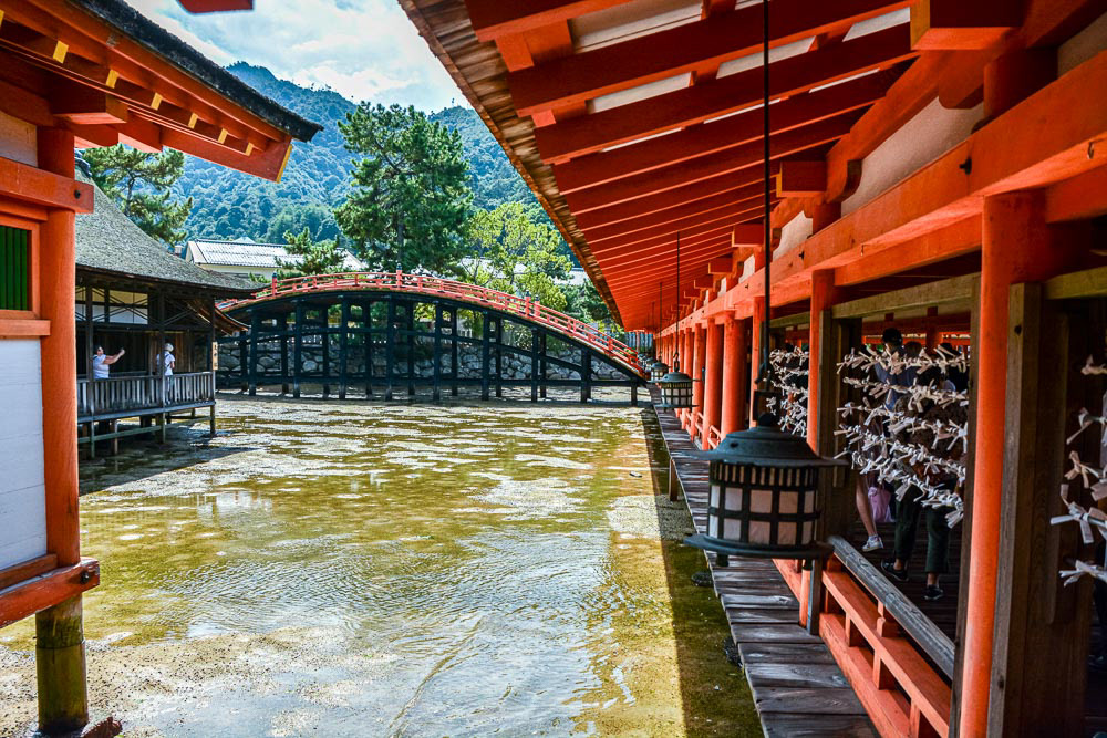 Itsukushima Shrine, Omikuj (fortunes written on strips of paper at Shinto shrines and Buddhist temples) line the hall. Sorabaci (arched timber bridge) in the background.