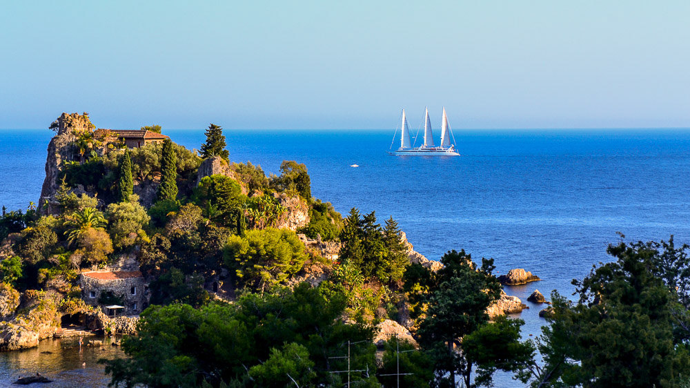 A luxury sailing yacht passes behind Isola Bella.