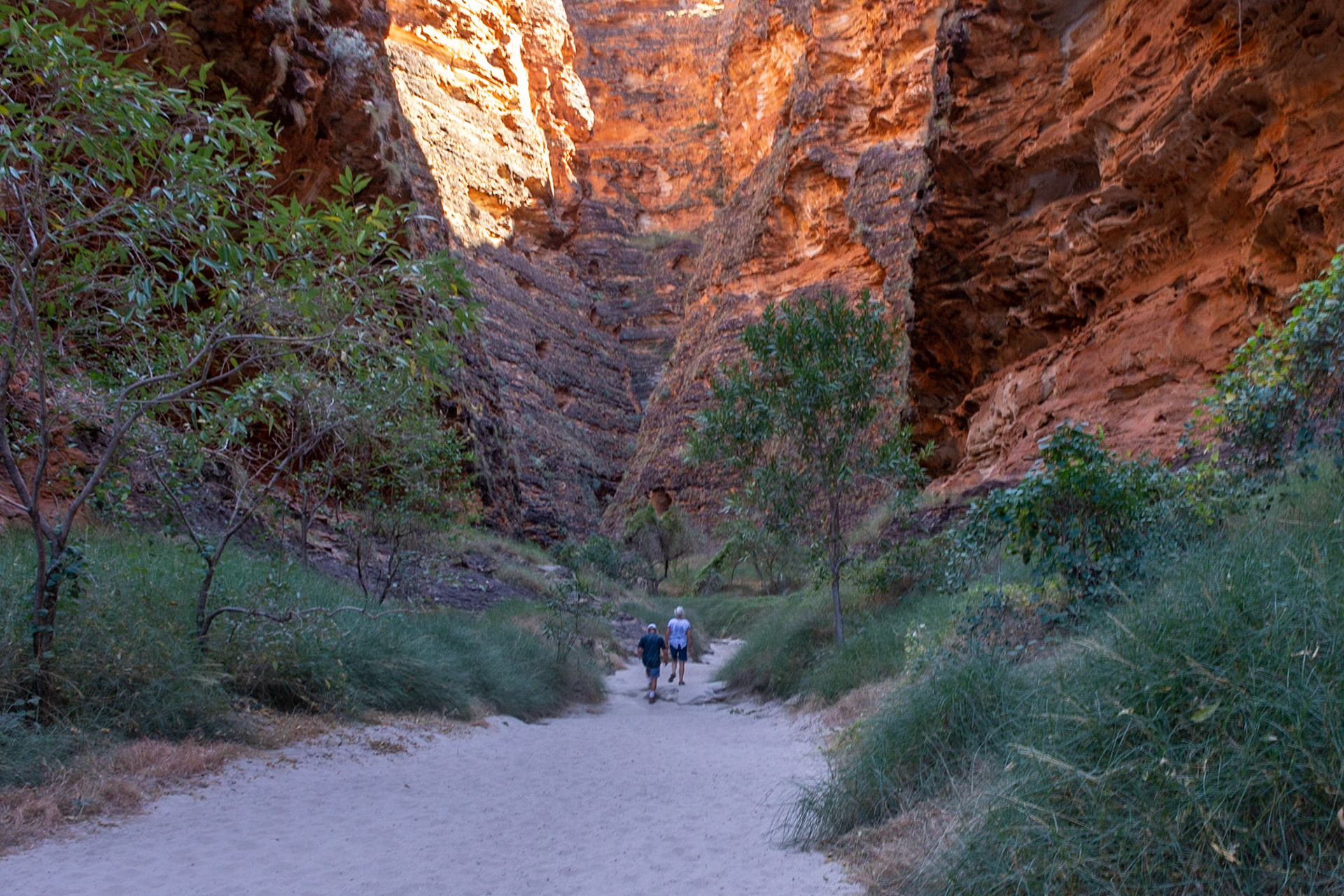 The magnitude of the adjacent sandstone cliffs dwarfs hikers into Cathedral Gorge