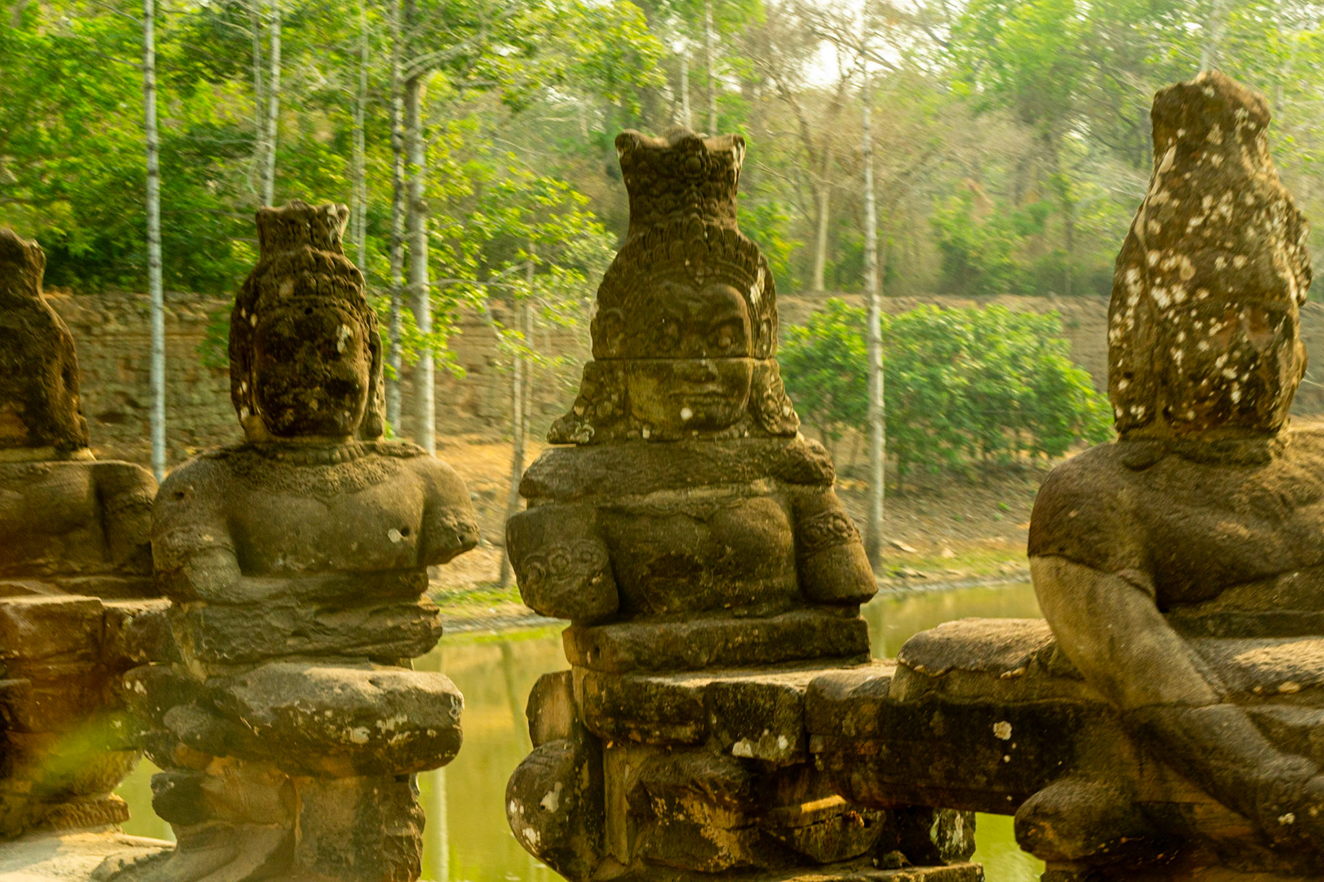 Sandstone statues greet us we cross the moat at the south gate to Angkor Thom.