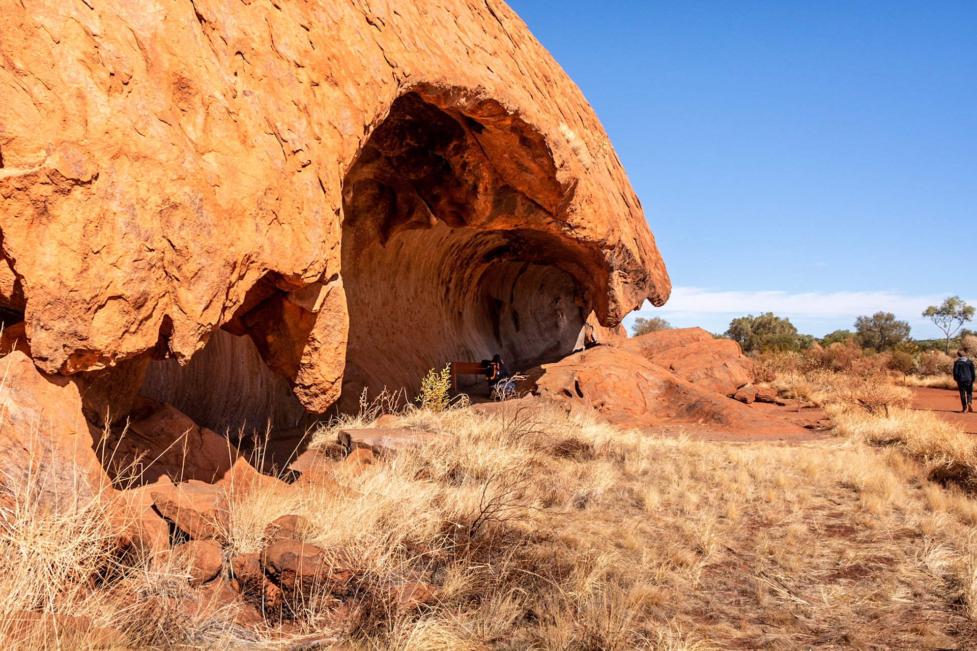 A breaking wave shaped rock overhang attracts the attention of a photographer