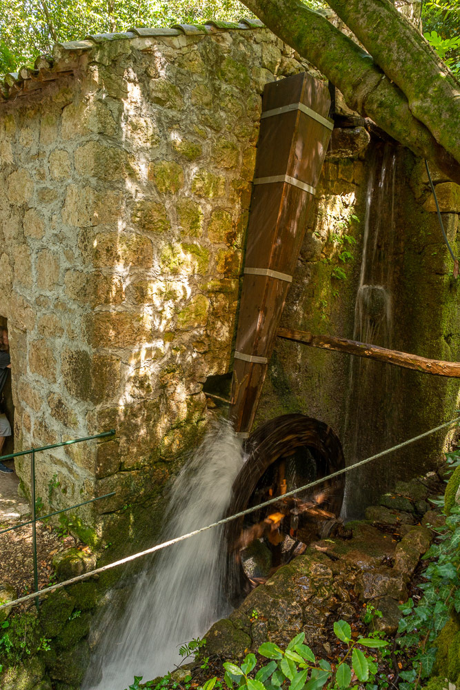 A side view of the chute and water wheel powering the mill inside the stone building.
