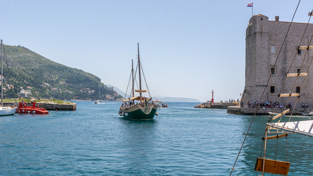 A tourist boat enters the Old Town Harbour past the fort walls.