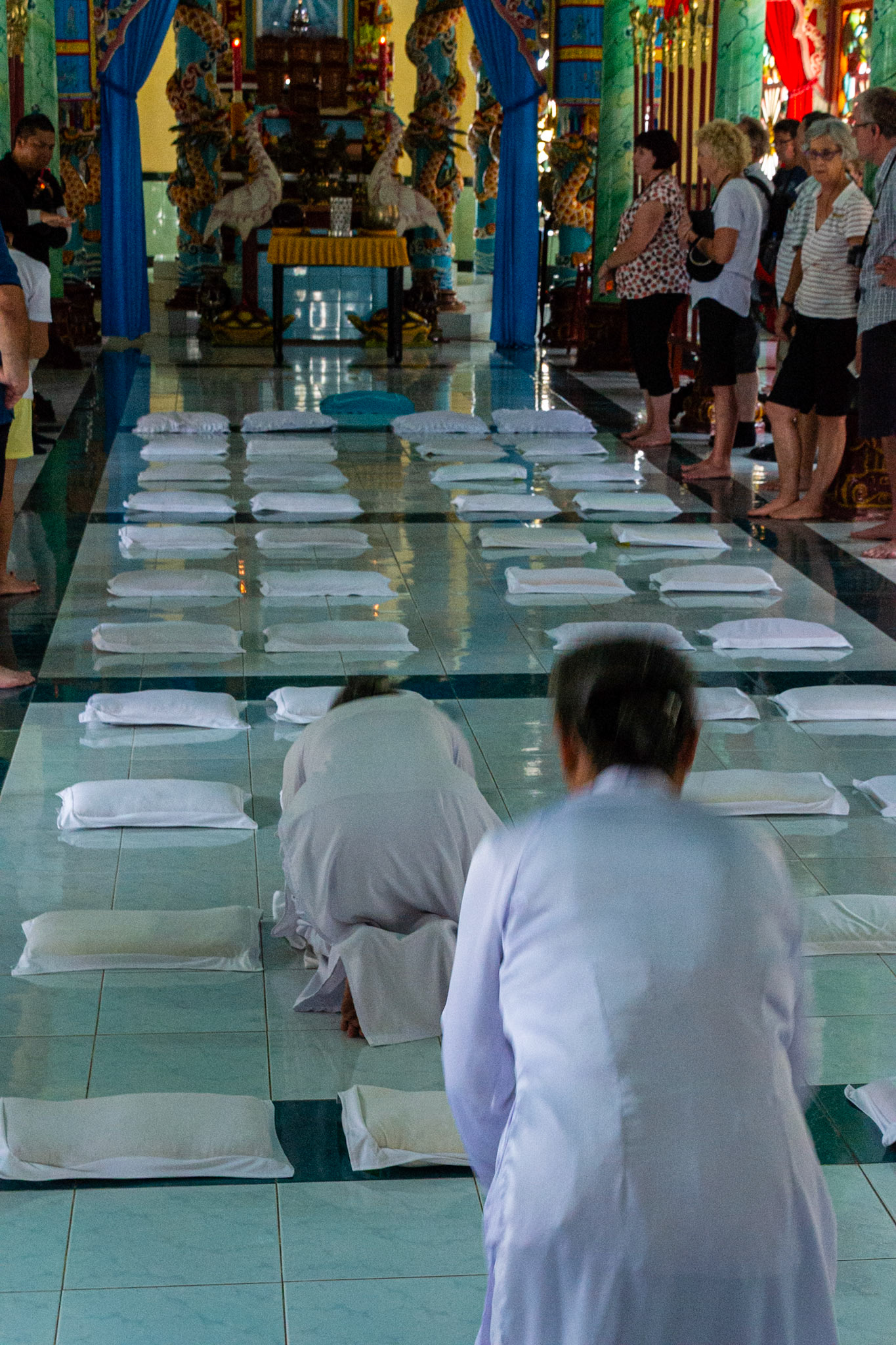 Cao Daist worshipers dressed in white robes. The name “Cao Dai” translates to “High Tower” or “High Place,” symbolizing the divine realm or supreme deity in the religion.
