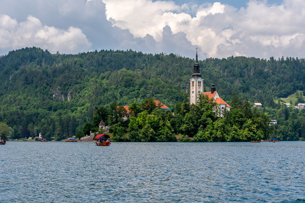 A plenta load of tourists in front of Bled Island with the Baroque Church of Mary and it's separate belltower.