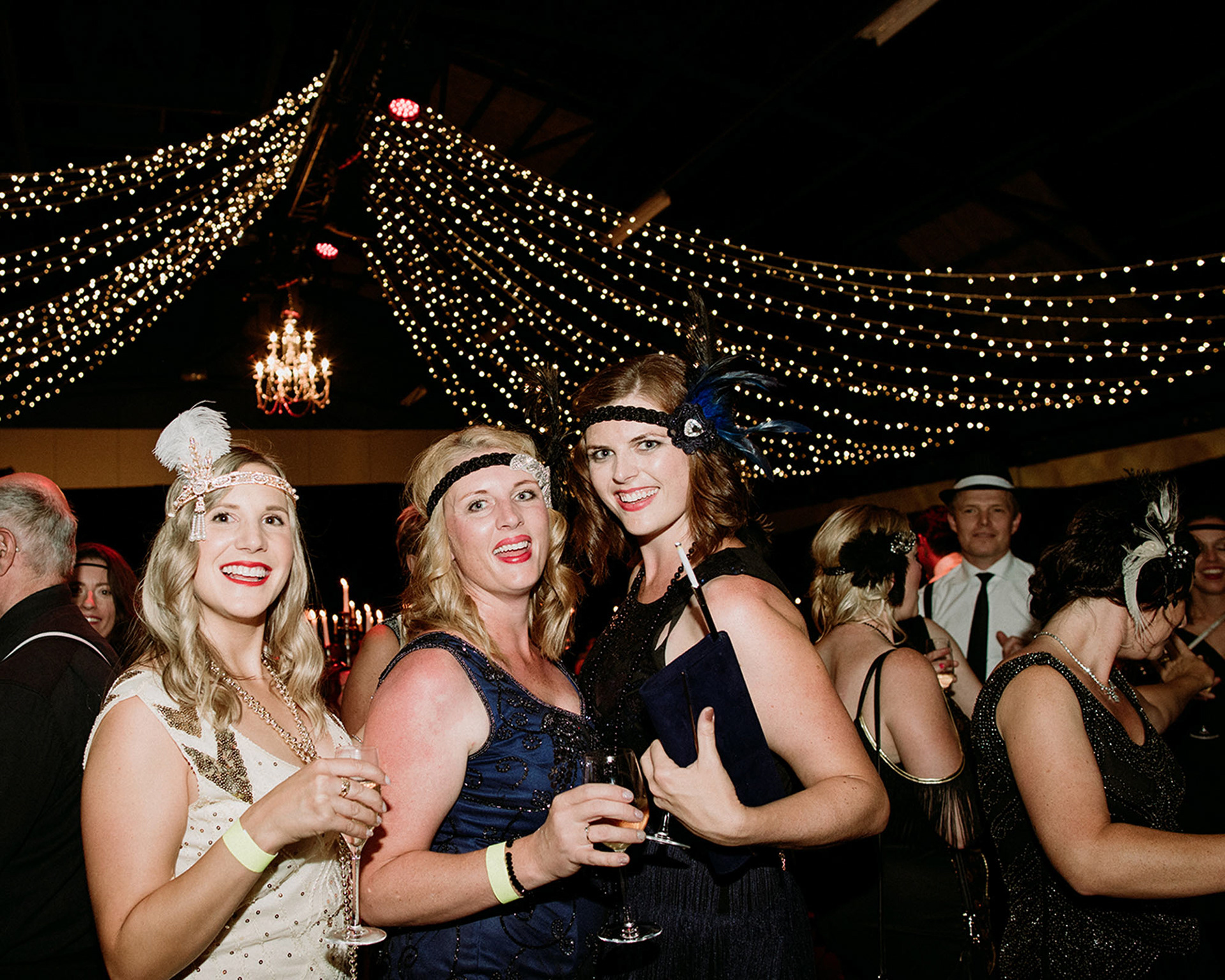 Women dressed in art deco evening wear smiling at Prohibition Party