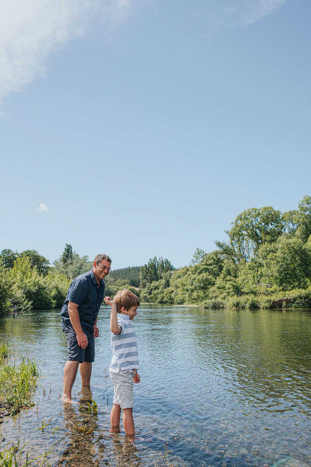 Father and son throwing stones riverside