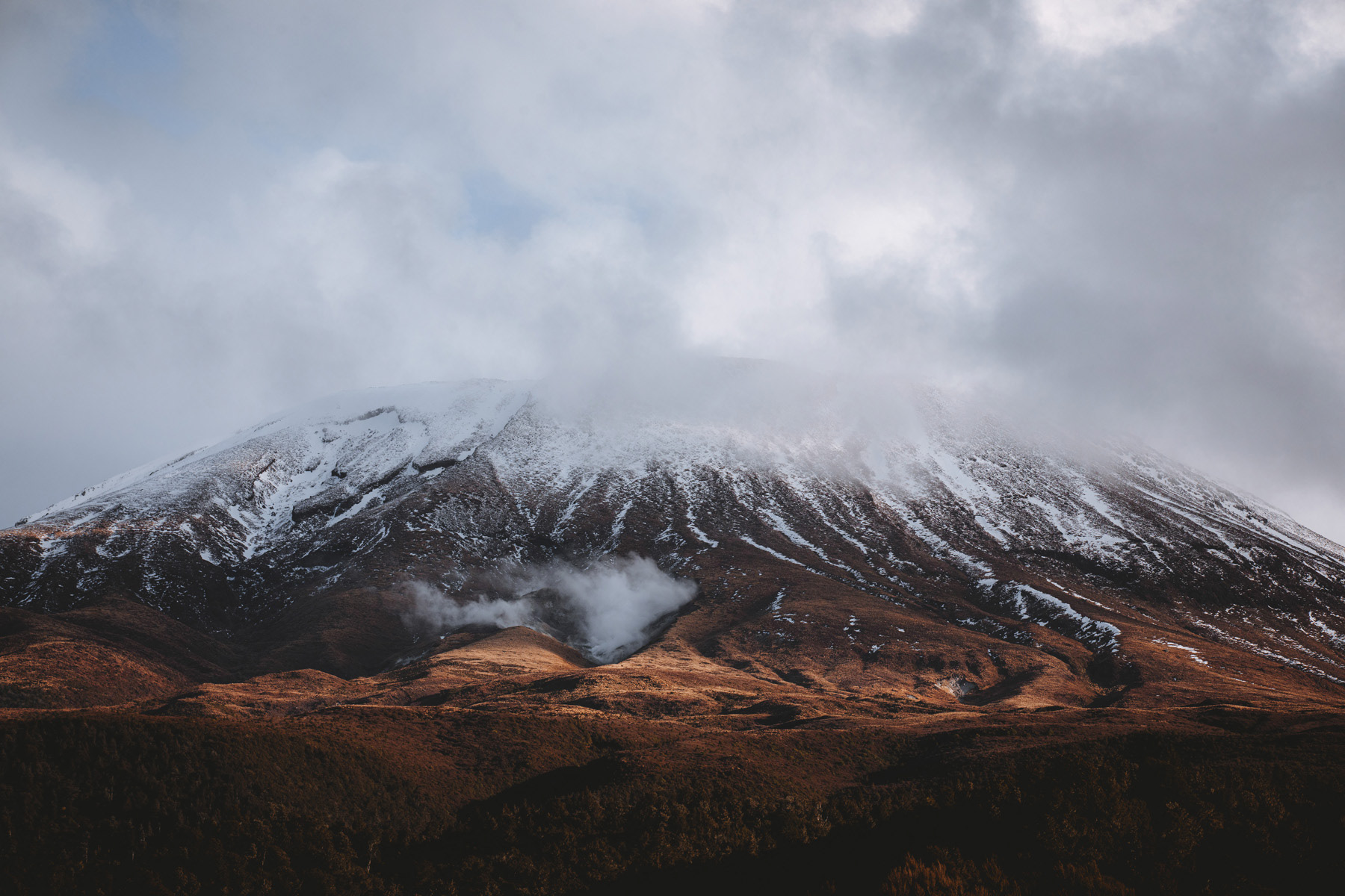 A side view of Mount Tongariro with cloud blanketing the top