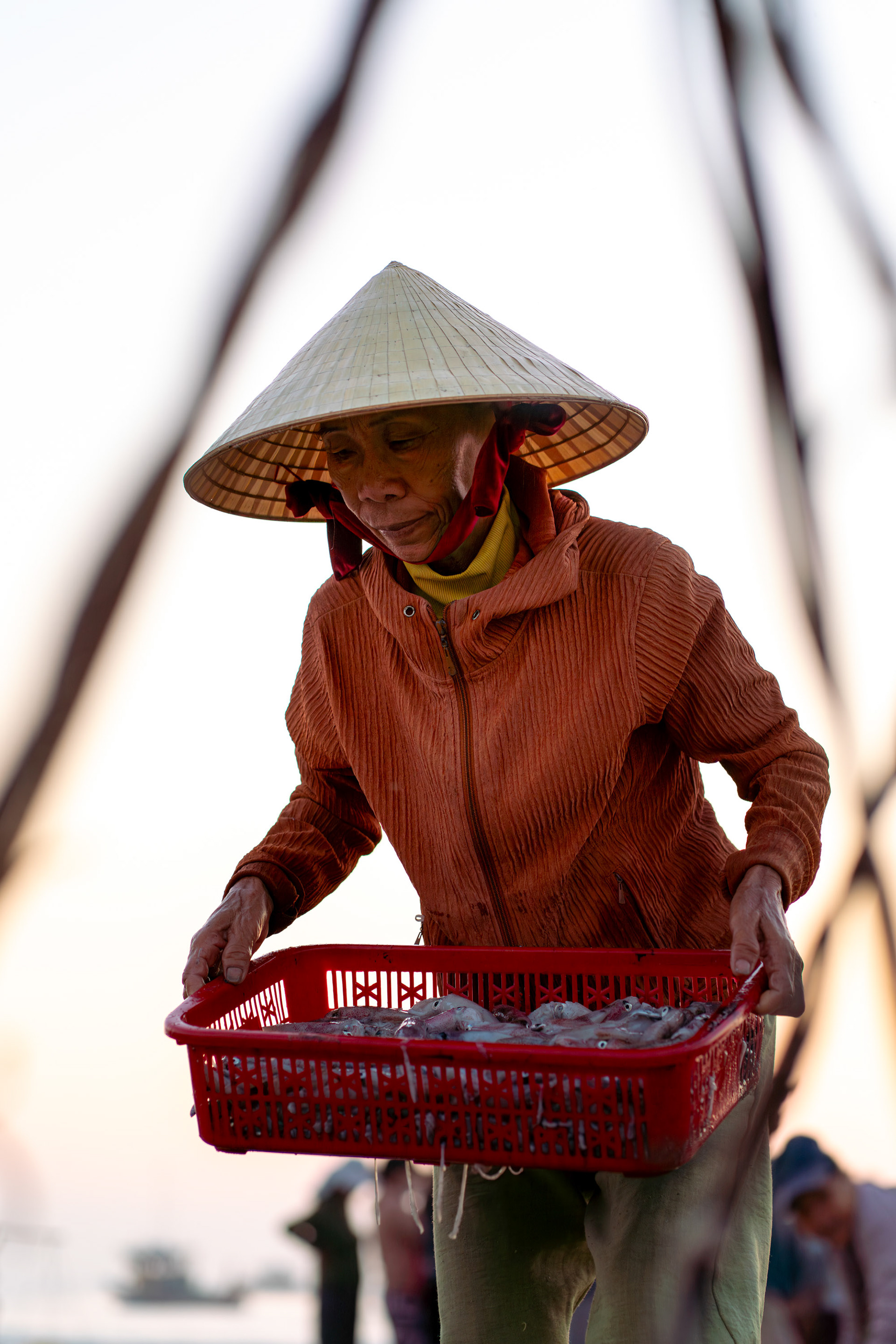 Vietnamese woman carrying baskets on a beach near Hoi An at sunrise.