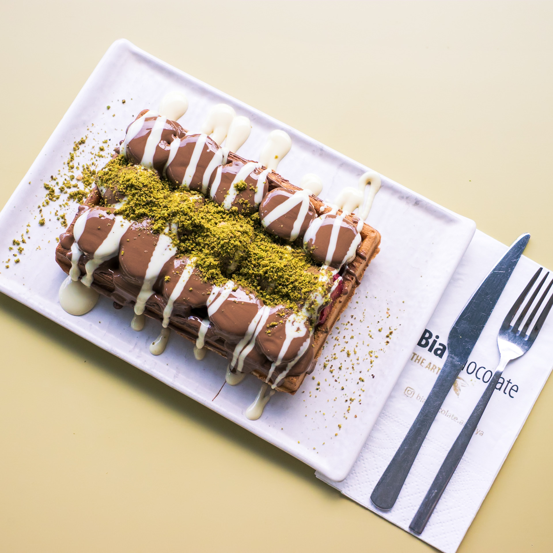 BELGIAN CHOCOLATE WAFFLE Lezzetli Belçika Çikolata usulü Waafle’ımız beyaz ve bitter çikolata opsiyonu ile üzerinde Antep fıstığı ile servis edilir.