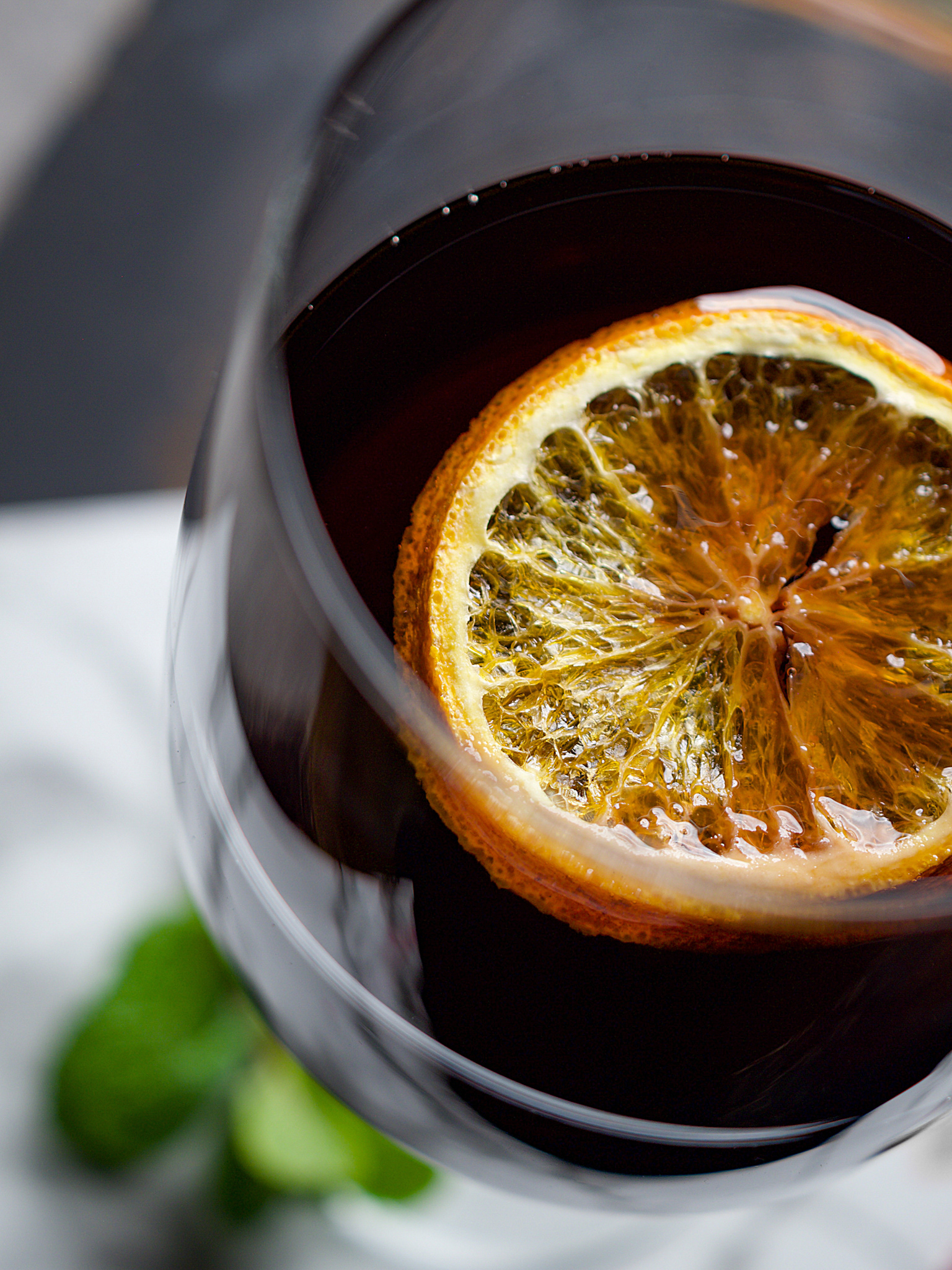 Detailná food fotografia pohára červeného vína s plátkom sušenej pomarančovej kôry na hladine - Jemné svetlo - Pohľad zhora - Autor: Jana Kollarova