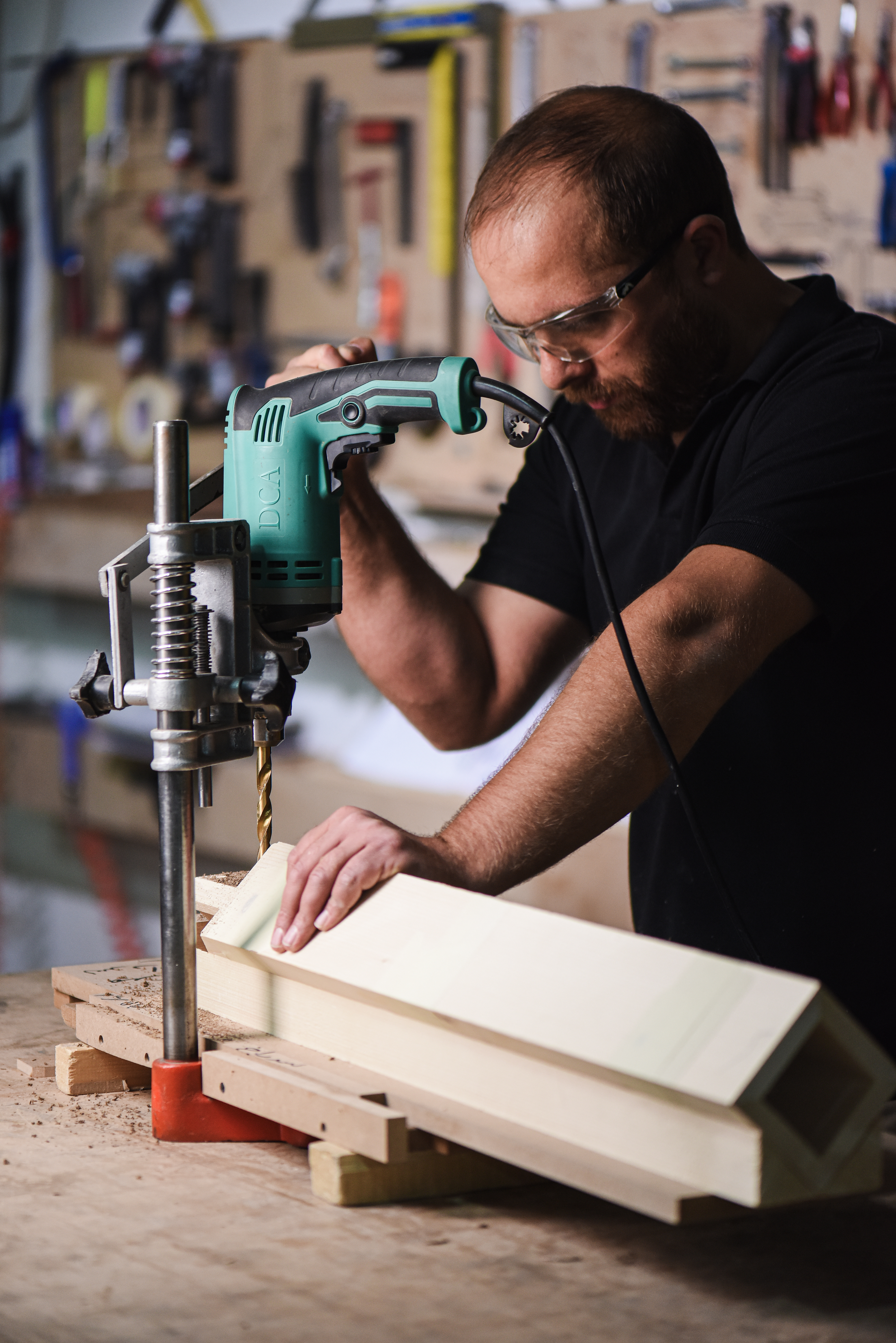 Drill press on timber; hand pressure guiding feed; clean chips.