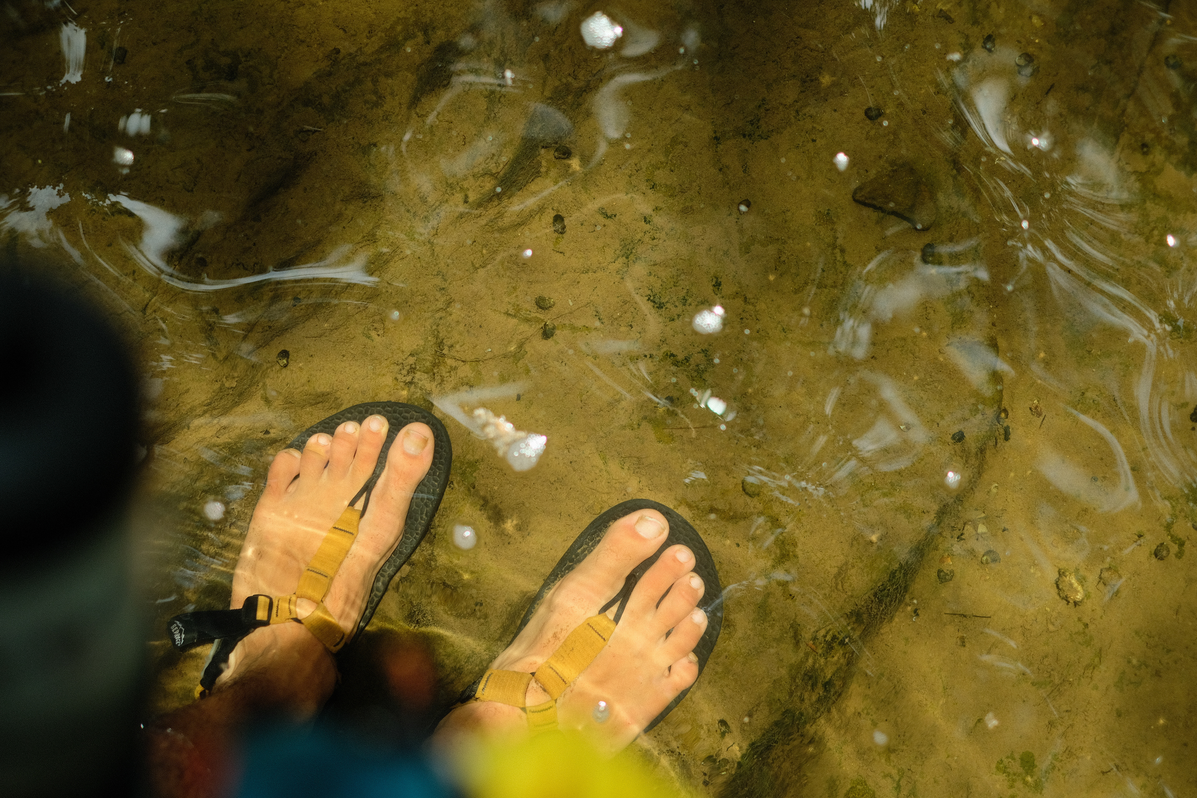 Sandals-clad feet relaxing in the water