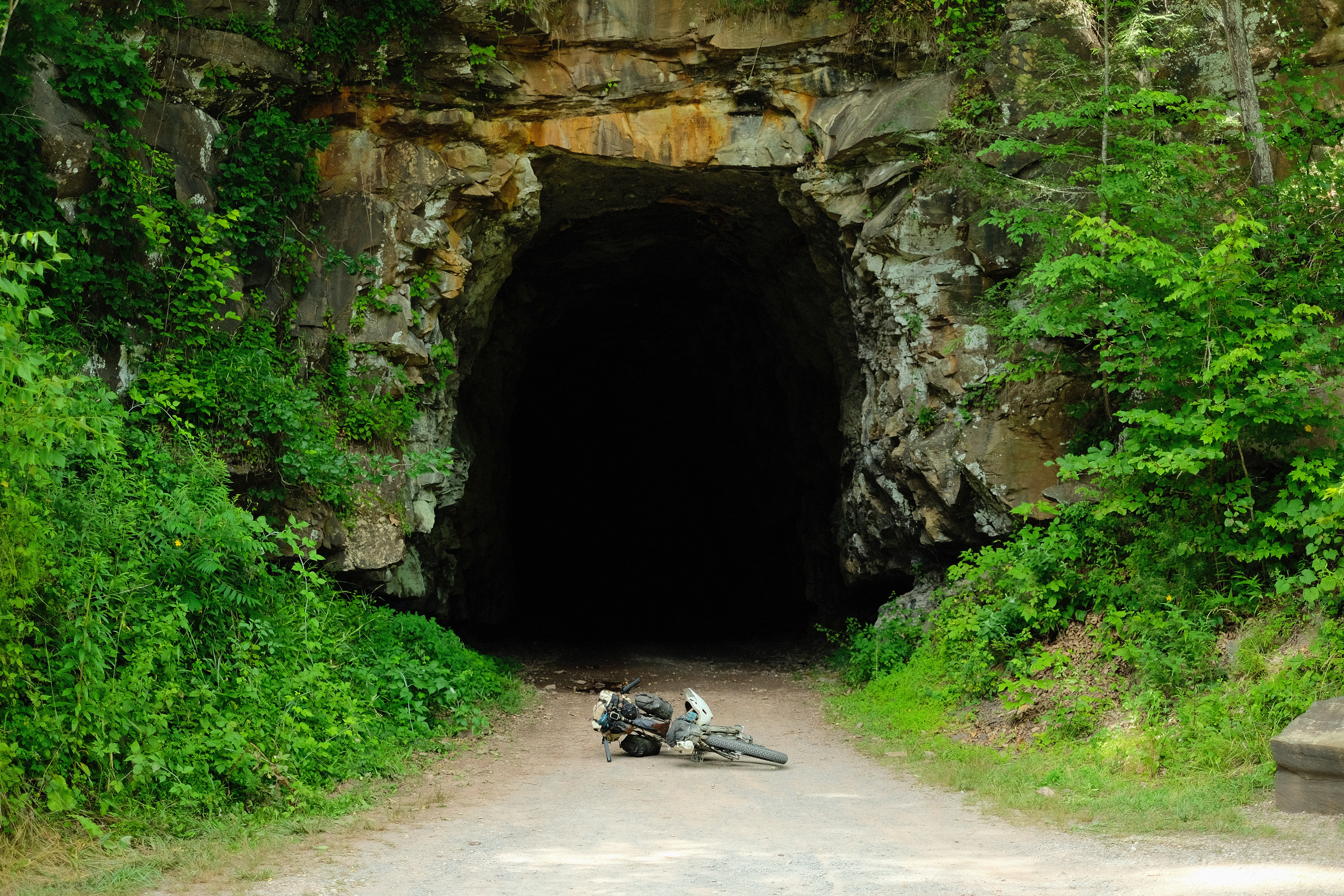 The bike lies on the ground, anticipating a spooky old train tunnel