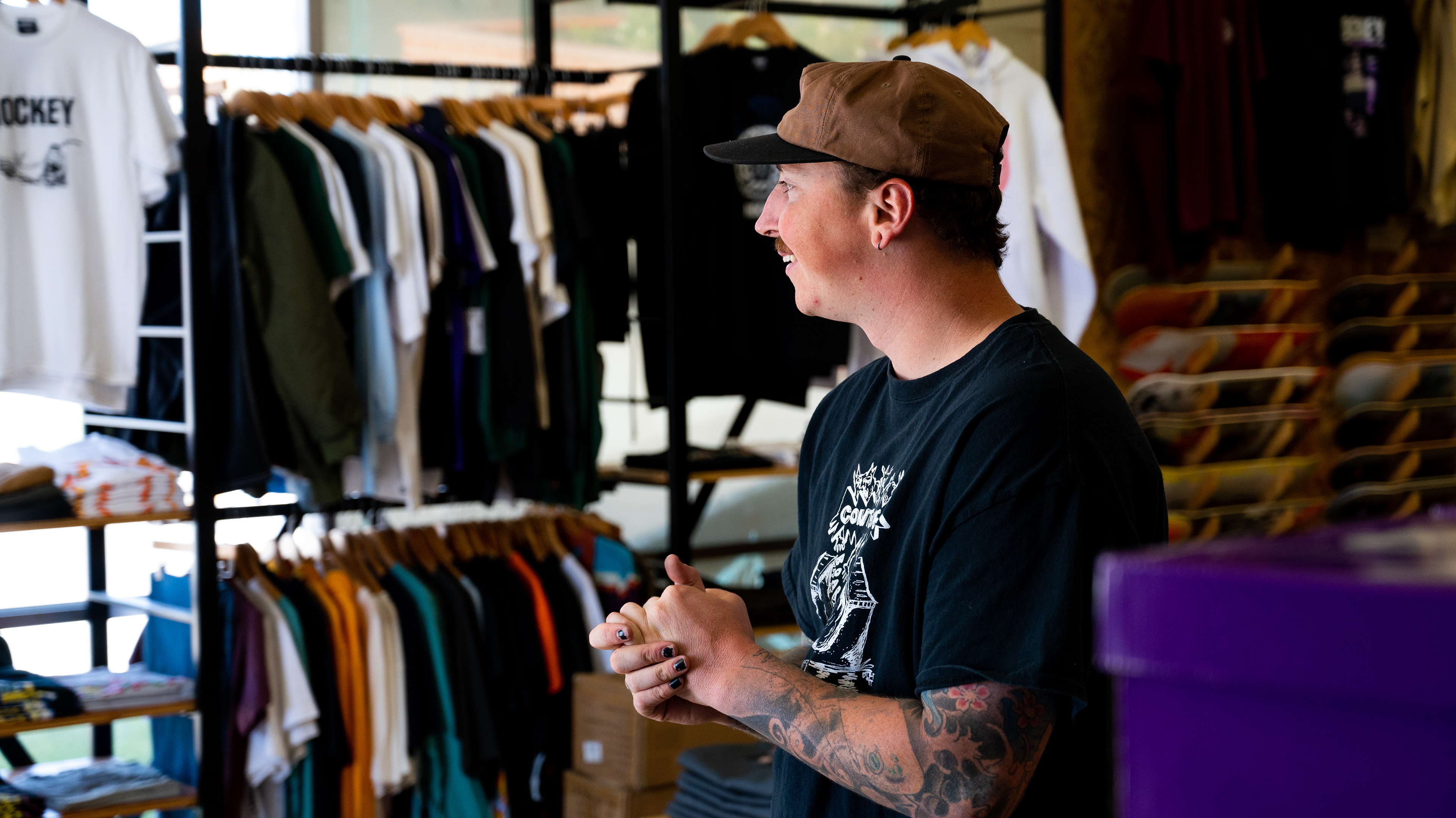 Dylon converses with customers about his collection of tattoos he has received over the years, as well as the culture that exists in Contenders Boardshop on April 14. Photo by DEVON JAMES.