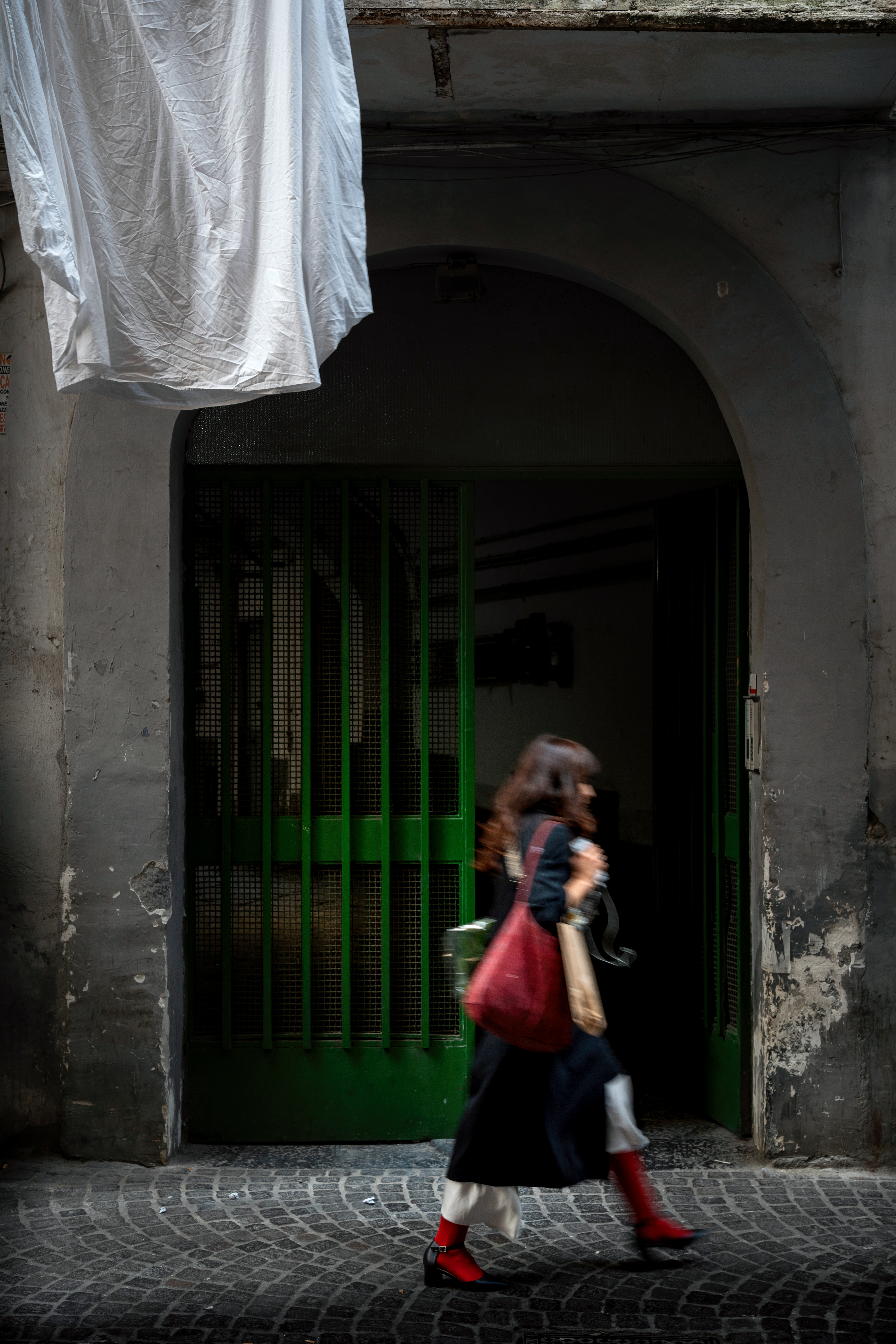 Woman with red socks walking past a green doorway in italy.