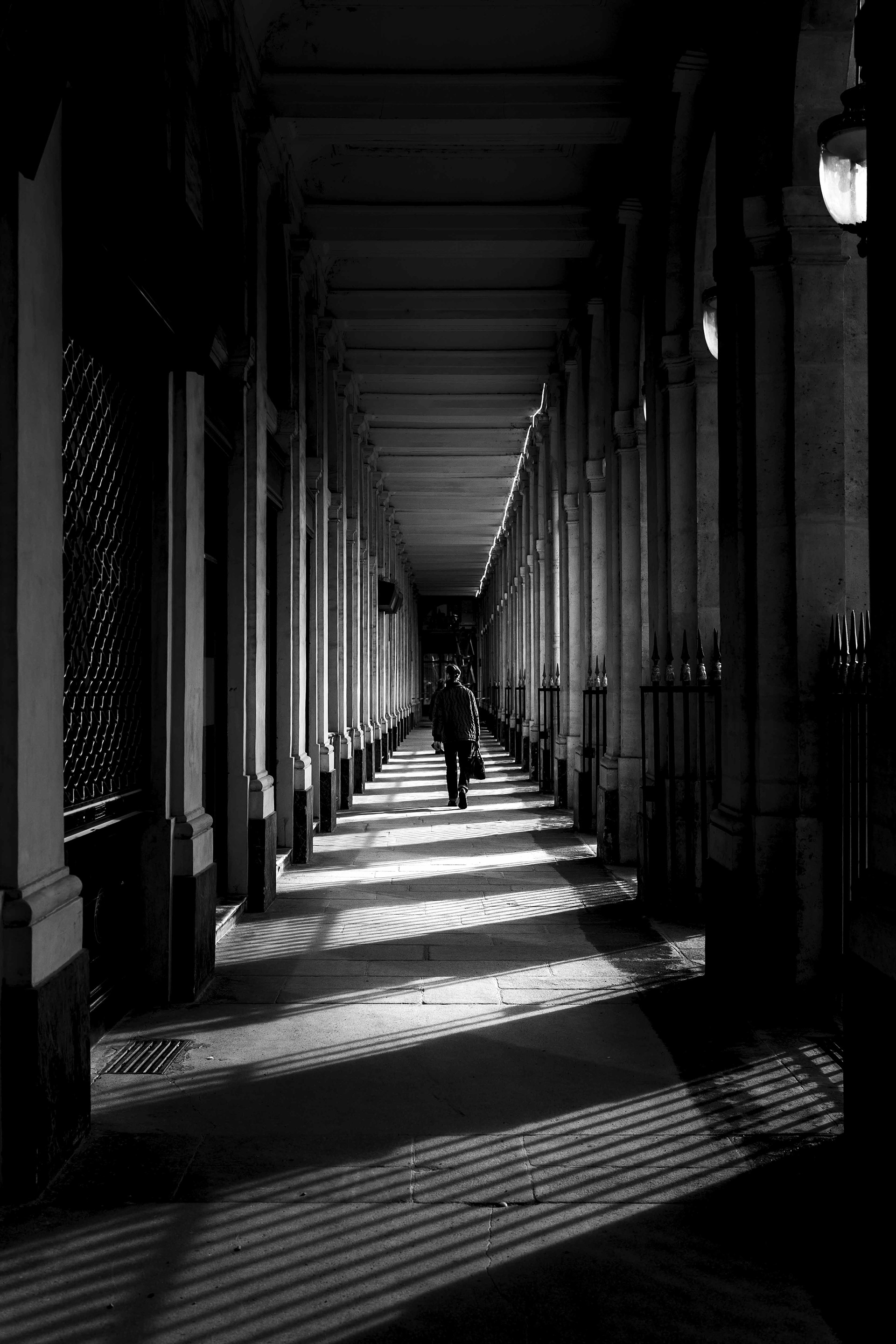 pedestrian walking through the arcades of the Palais-Royal in Paris.