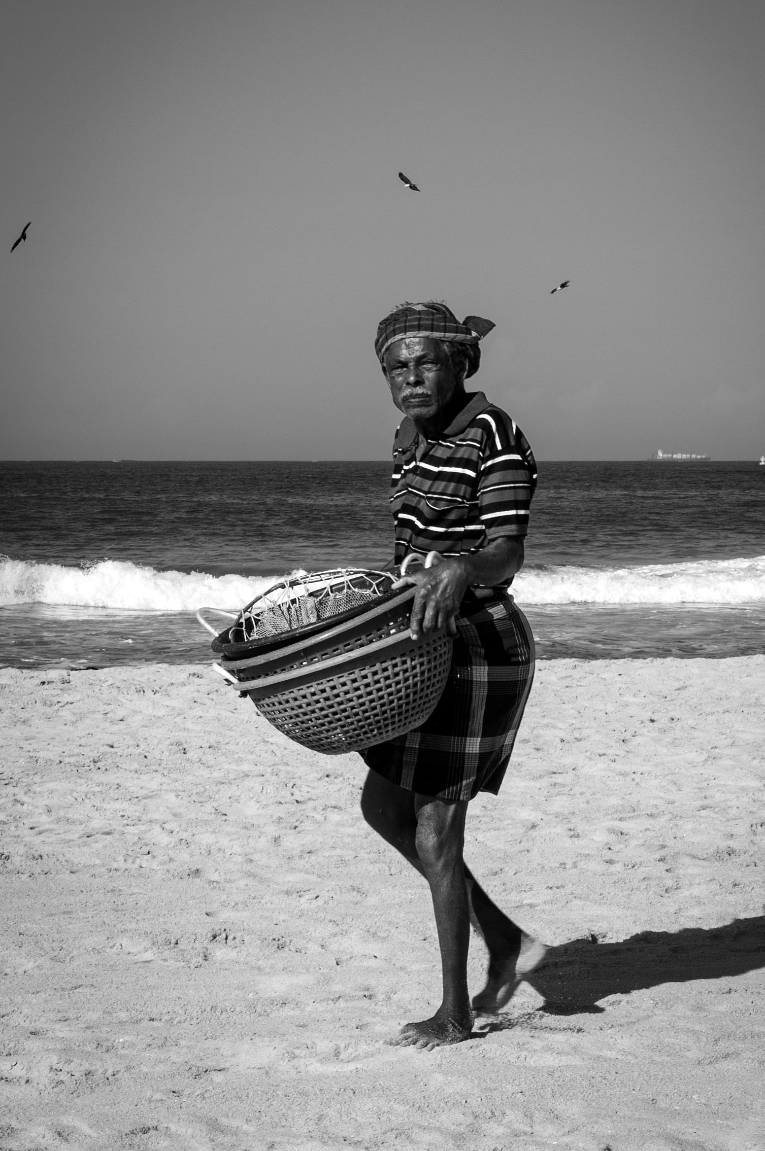 Fisherman carrying baskets on the beach in Kerala, India.