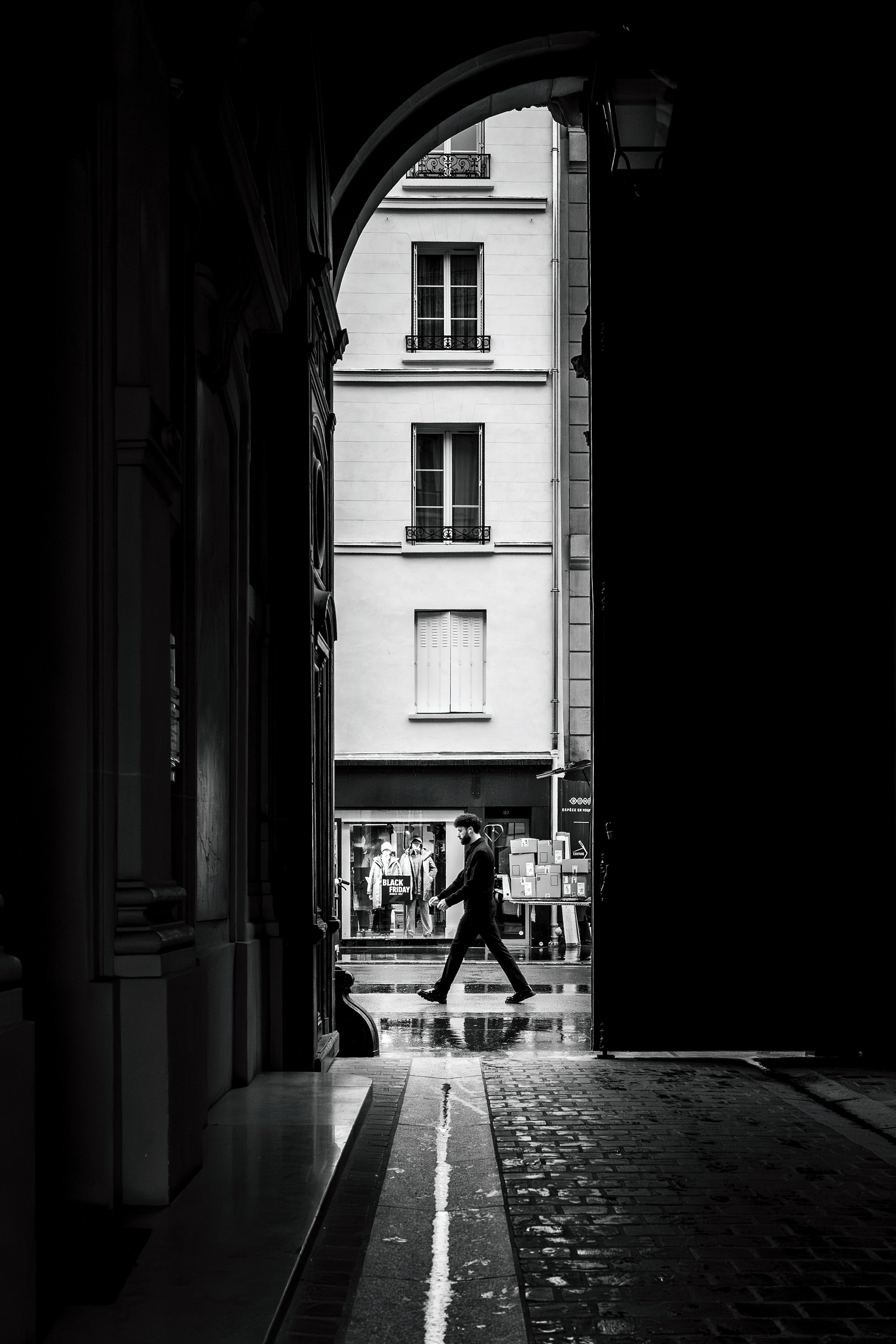 Pedestrian framed by a dark passageway in Paris.