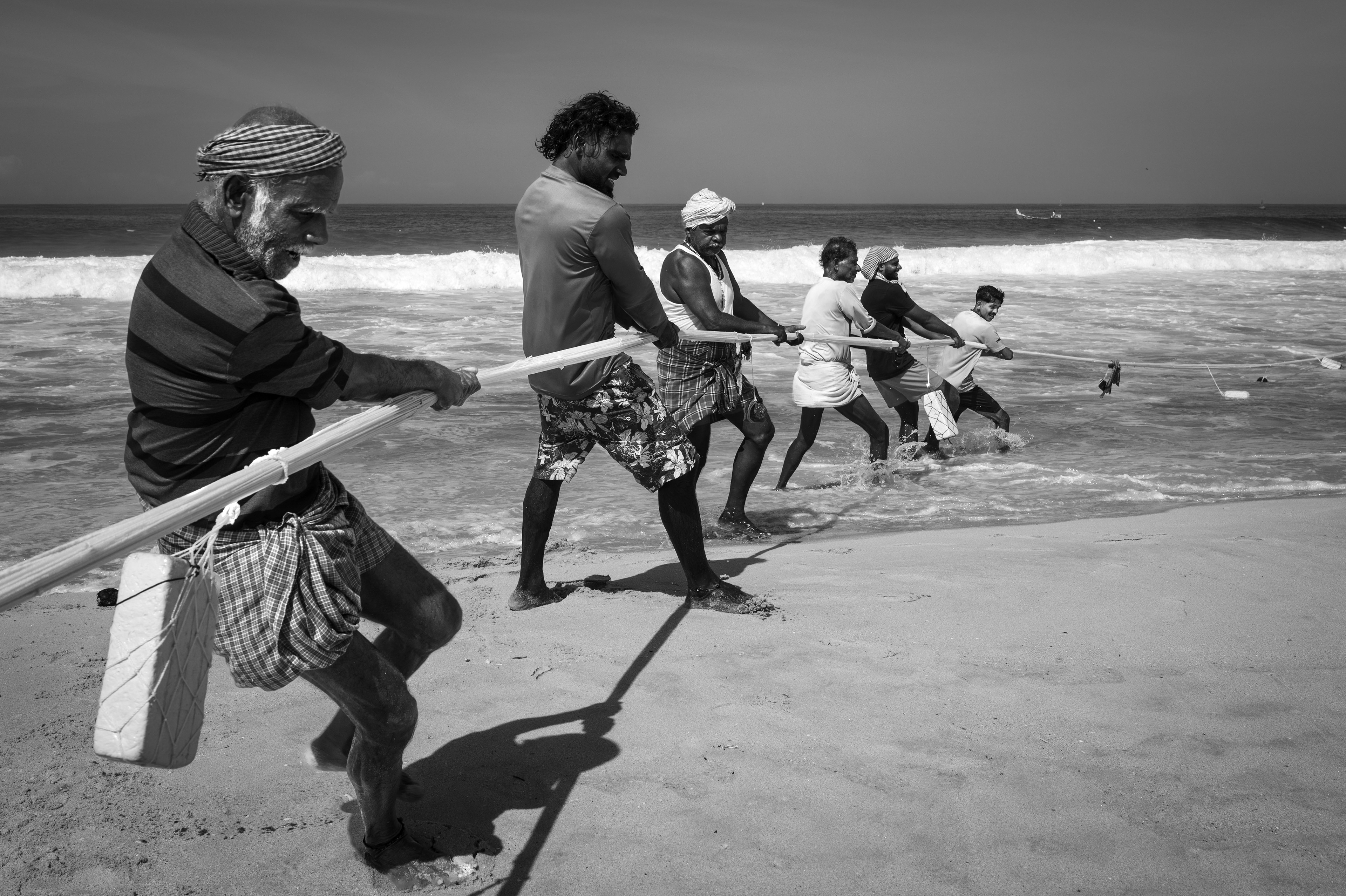 Fishermen pulling a boat from the sea on the Kerala coast.
