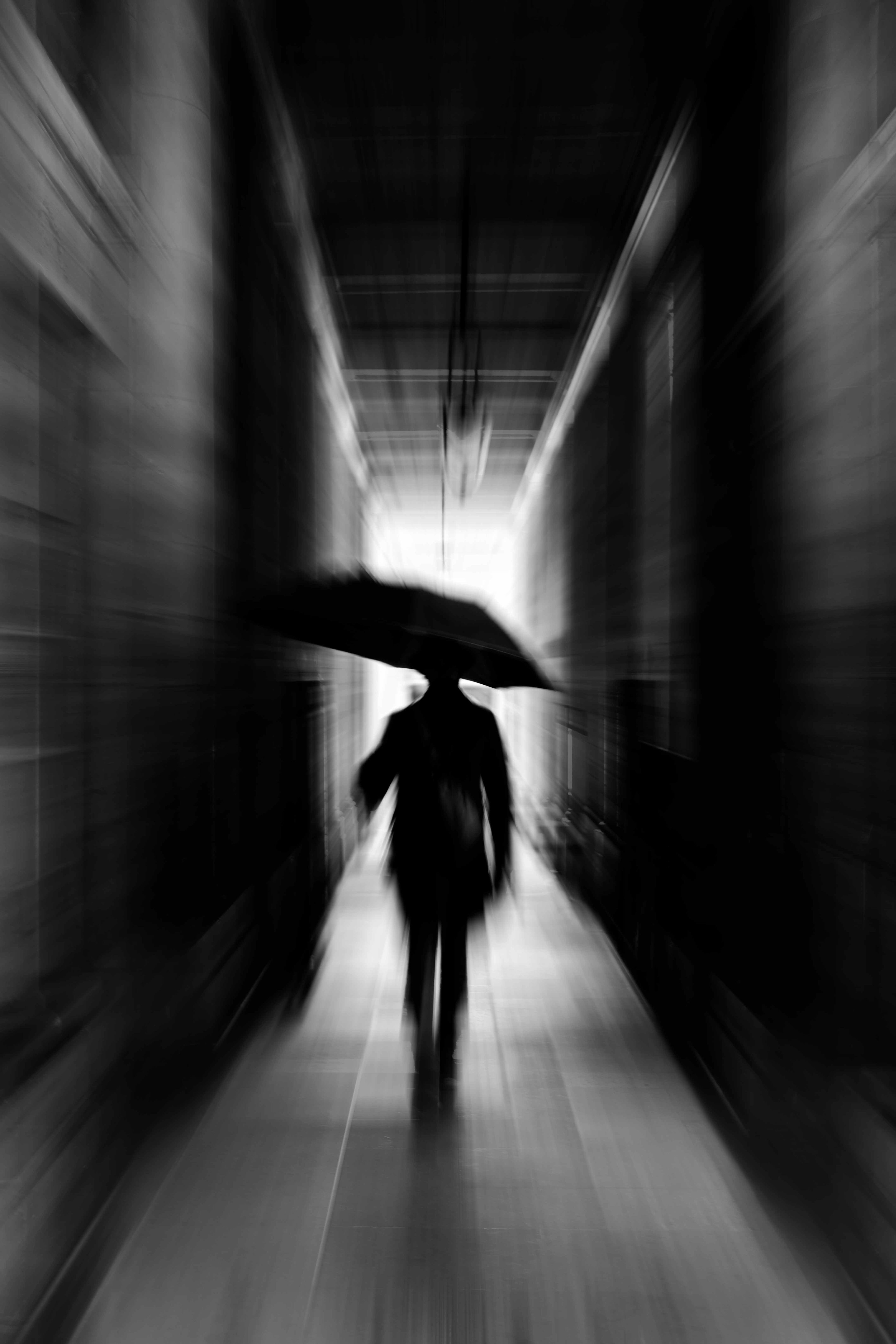 Blurred silhouette with an umbrella in a Paris passageway.
