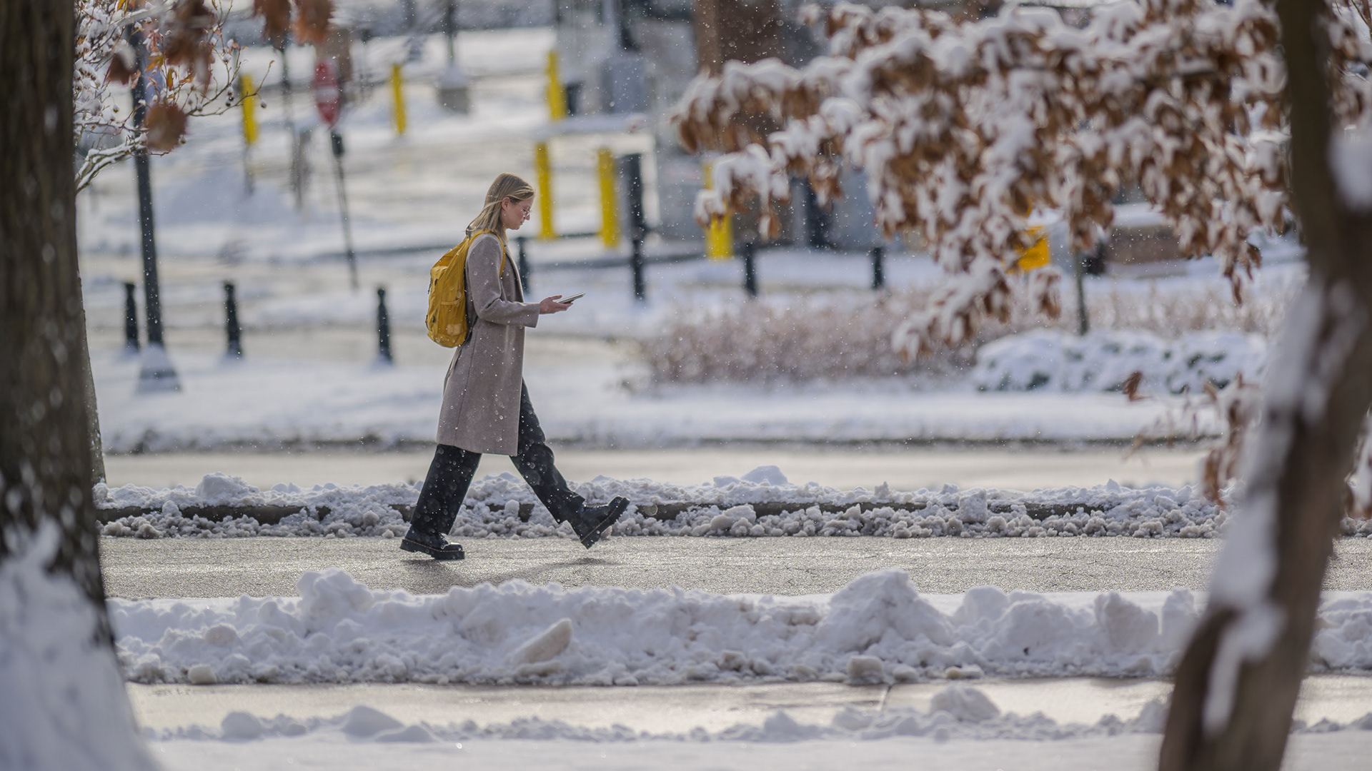A student crosses campus during a winter snowfall.