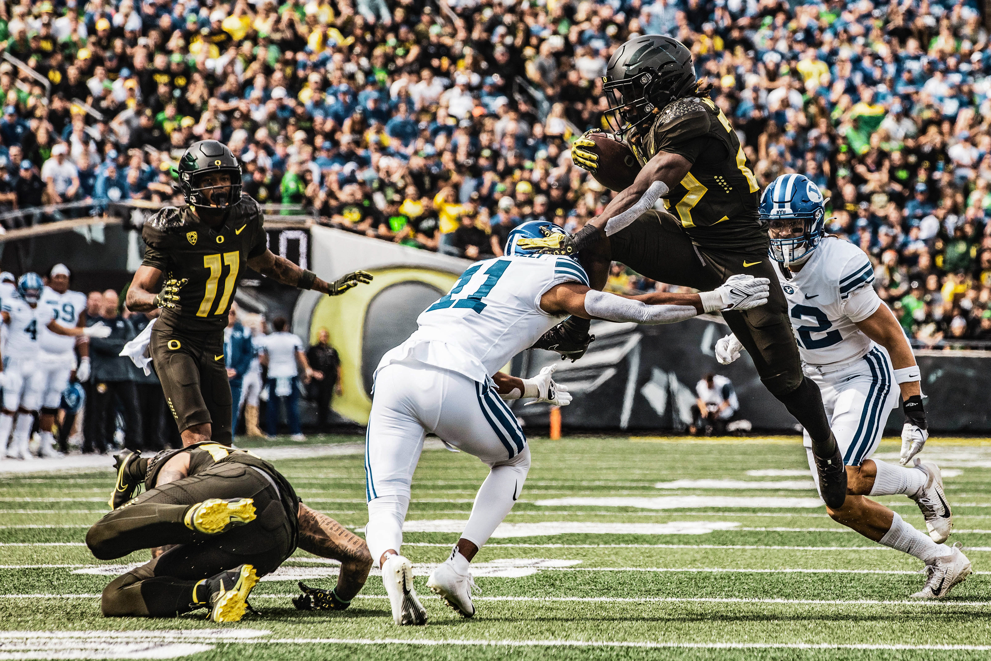Sophomore running back Noah Whittington (22) leaps over Cougar defense in order to make a first down attempt. University of Oregon Ducks Football defeat the BYU Cougars in a home match at Autzen Stadium in Eugene, Ore., on Sep. 17, 2022. (Maddie Stellingwerf/Emerald)