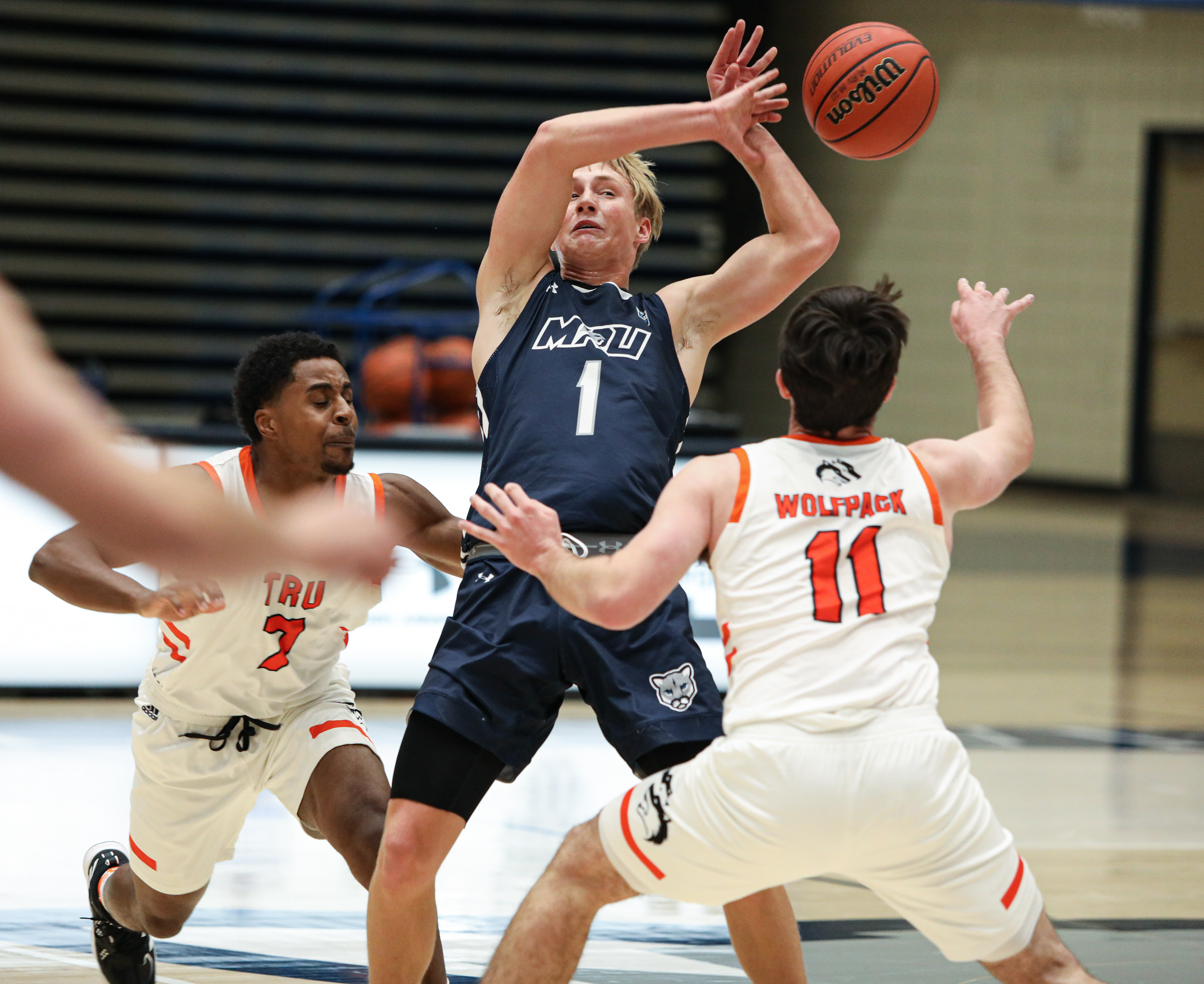 Mount Royal University Cougars guard Holt Tomie, center, loses the ball to Thompson Rivers University Wolfpack 's two players at the Mount Royal gymnasium in Calgary on Friday, Oct. 15, 2021. The Cougars beat the Wolfpack by a score of 67-66 in Alberta Colleges Athletic Conference men’s basketball action.