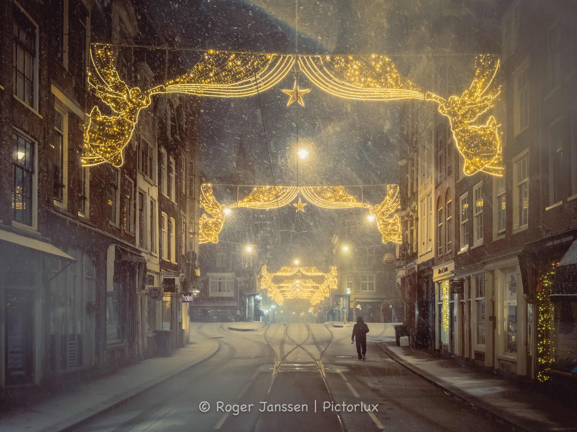 Lone pedestrian out on the street during a blue hour blizzard in Amsterdam.