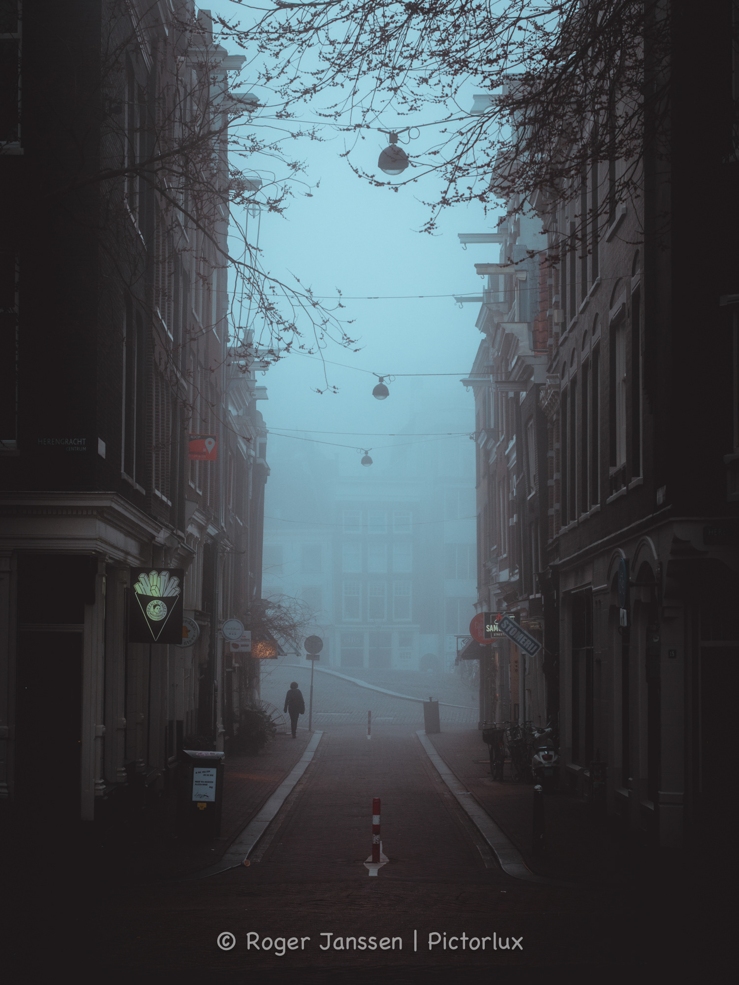 Lone pedestrian exiting the Oude Leliestraat in Amsterdam on a moody foggy morning.