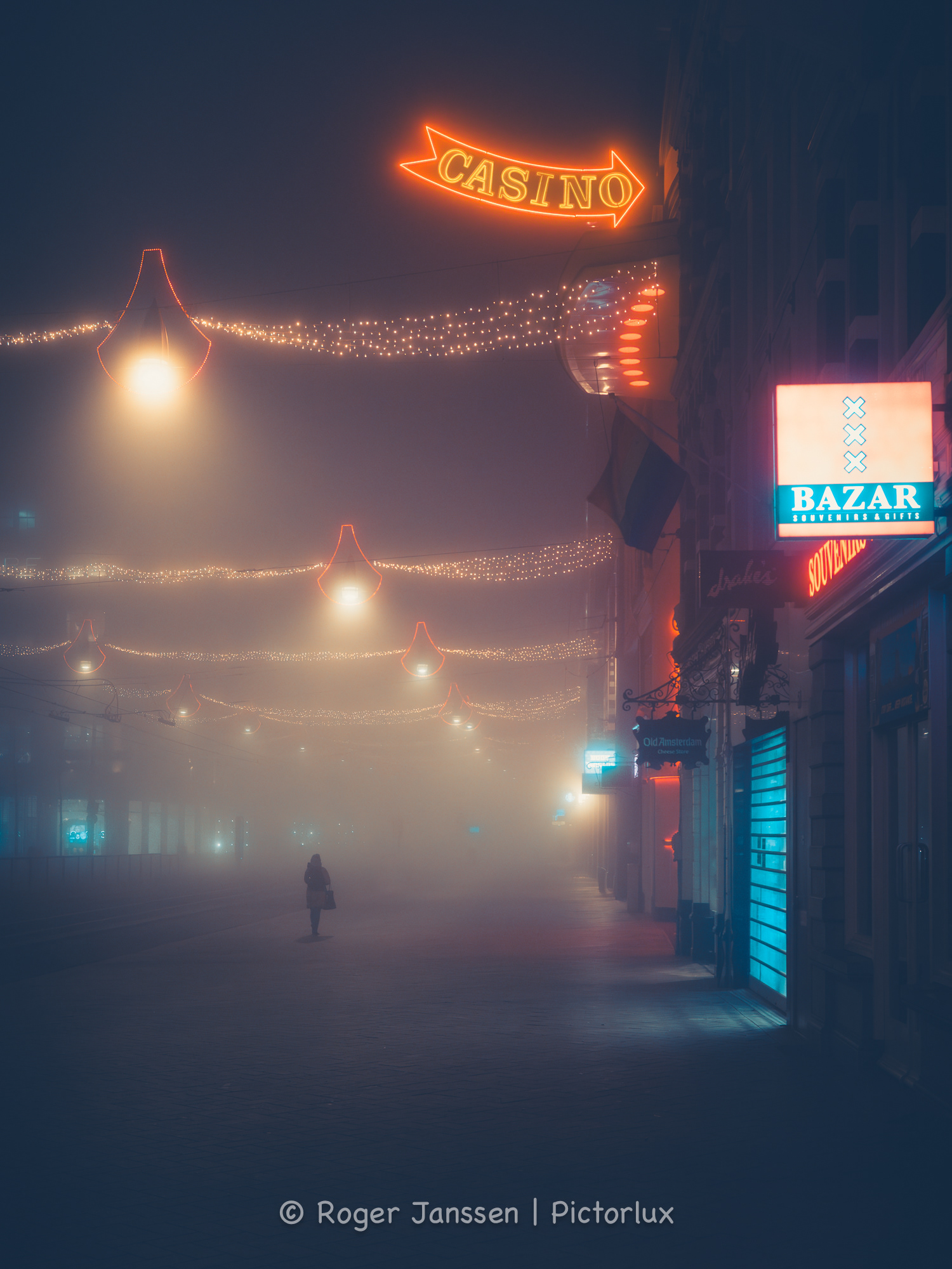 Lone street walker in a desolate Amsterdam on a foggy winter night during the Covid pandemic.