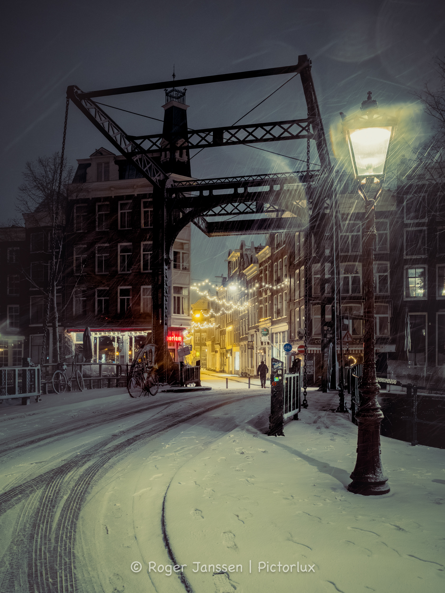 Lone pedestrian during a blizzard, crossing the Aluminiumbrug into the Staalstraat next to Café de Doelen in Amsterdam.