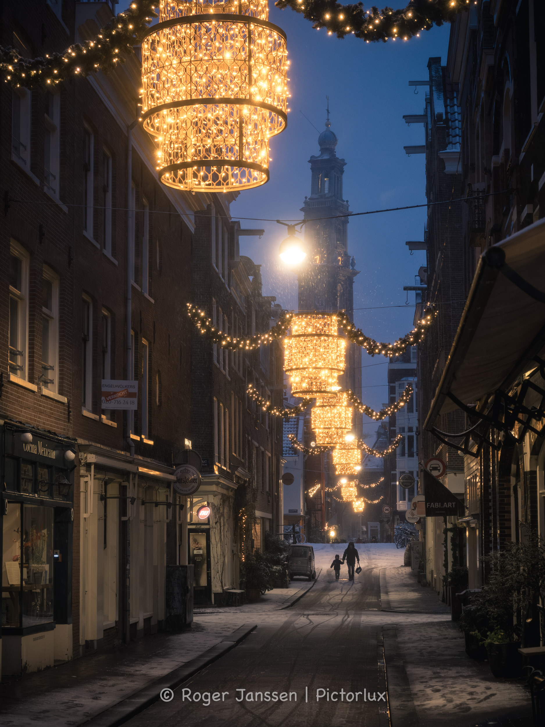 Met Westertoren op de achtergrond gedurende het blauwe uur brengt een ouder haar kind naar school in de Jordaan in Amsterdam.