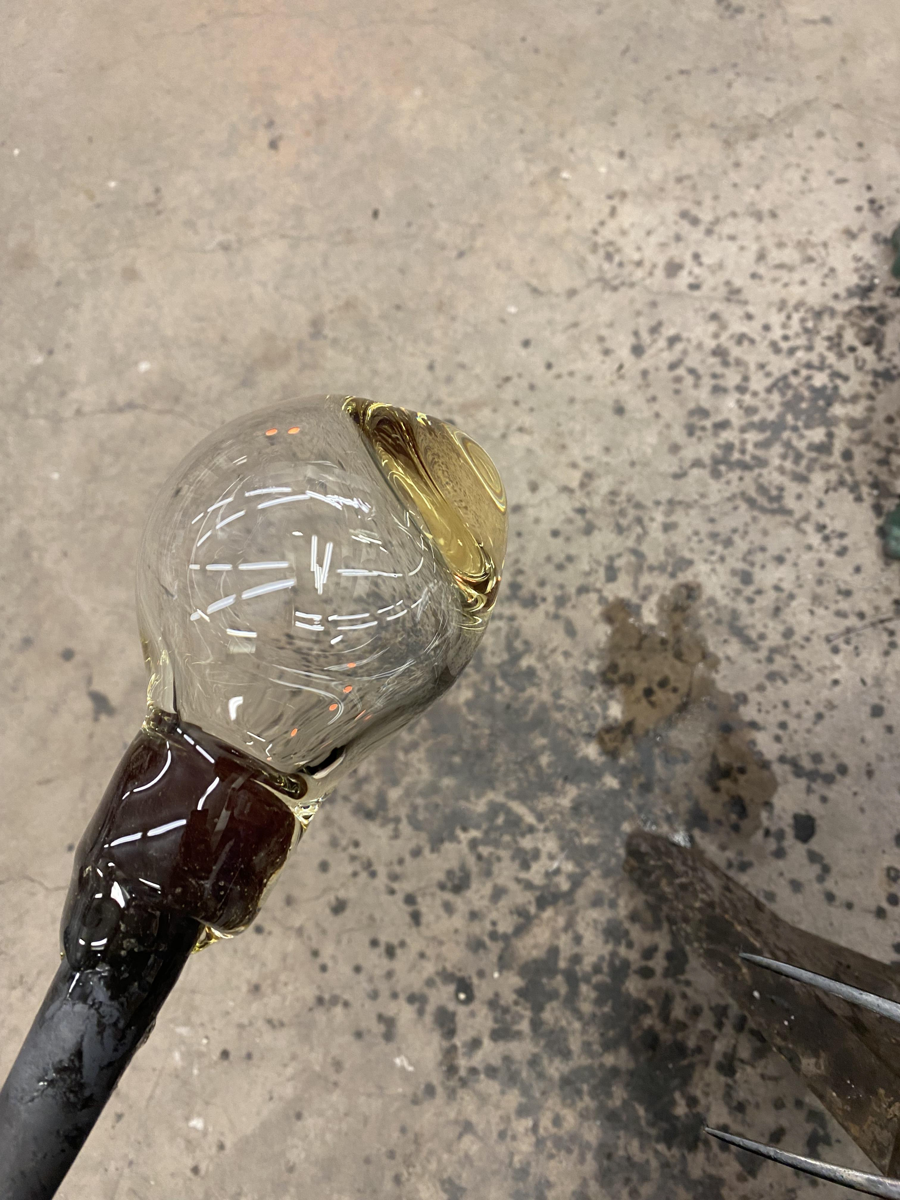Another attempt at blowing a bubble. However it went wrong due to not turning the pole enough when blowing down the pipe. To get the air to travel to the thicker part of the glass you have to heat just that area up as it travels to the hottest part.