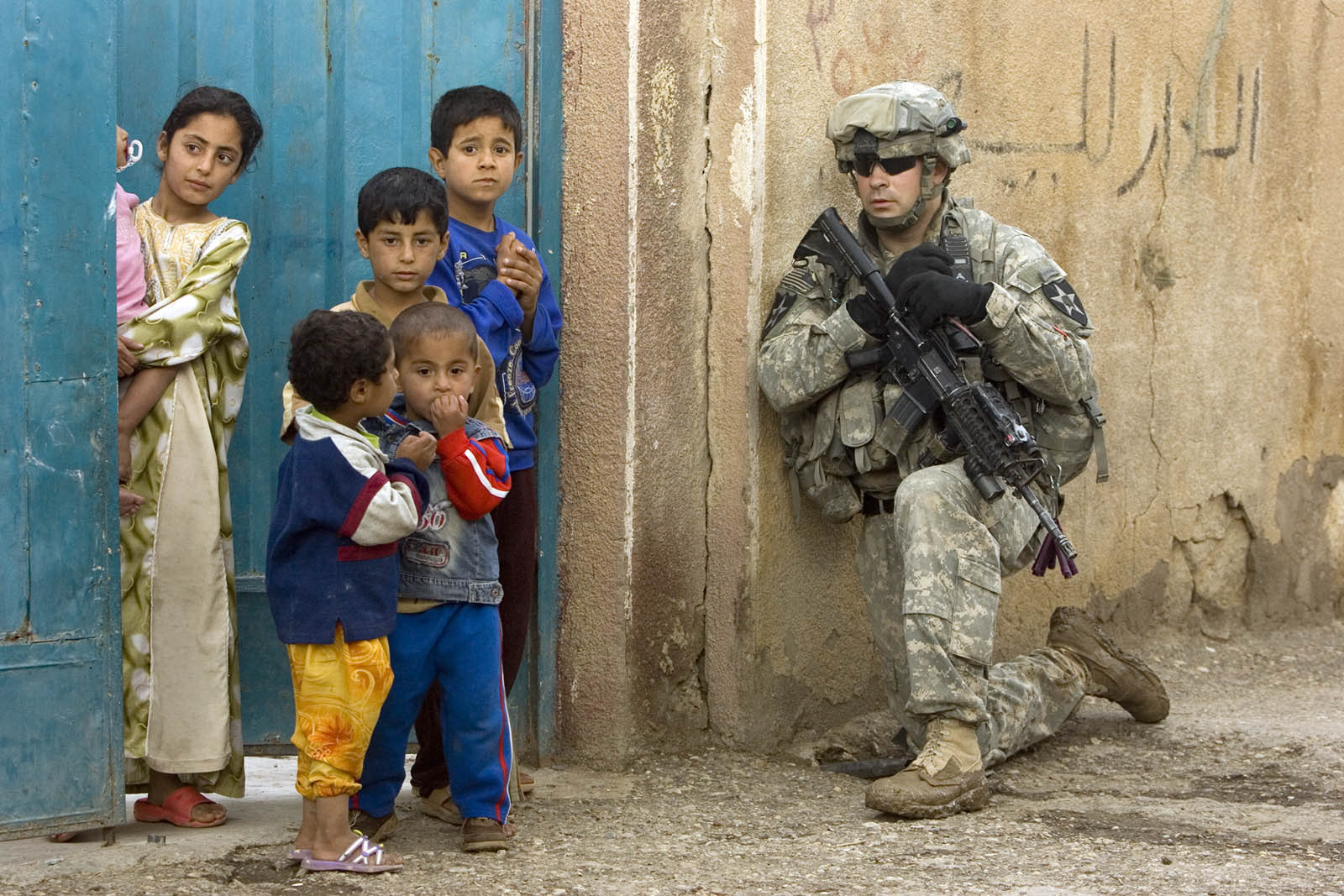 American soldier on patrol as a local Iraqi kids look on in Ramadi.