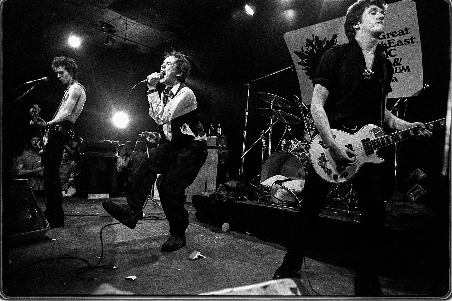 L-R, Sid Vicious on bass, Johnny Rotten, and Steve Jones on guitar. Drummer Paul Cook is hidden in background.