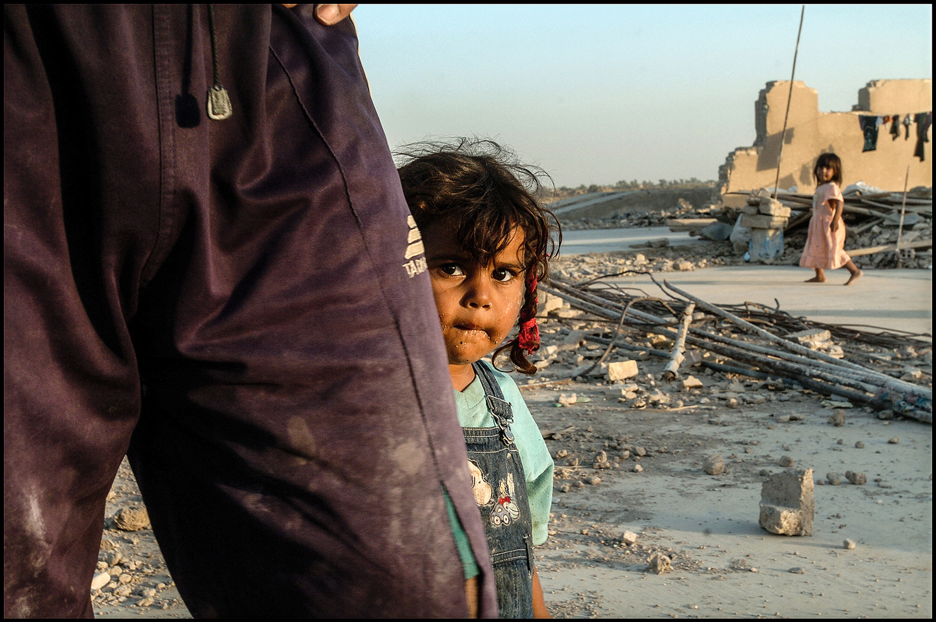 An Iraqi girl standing behind her father. He preferred not to be photographed or identified because of danger to his family.